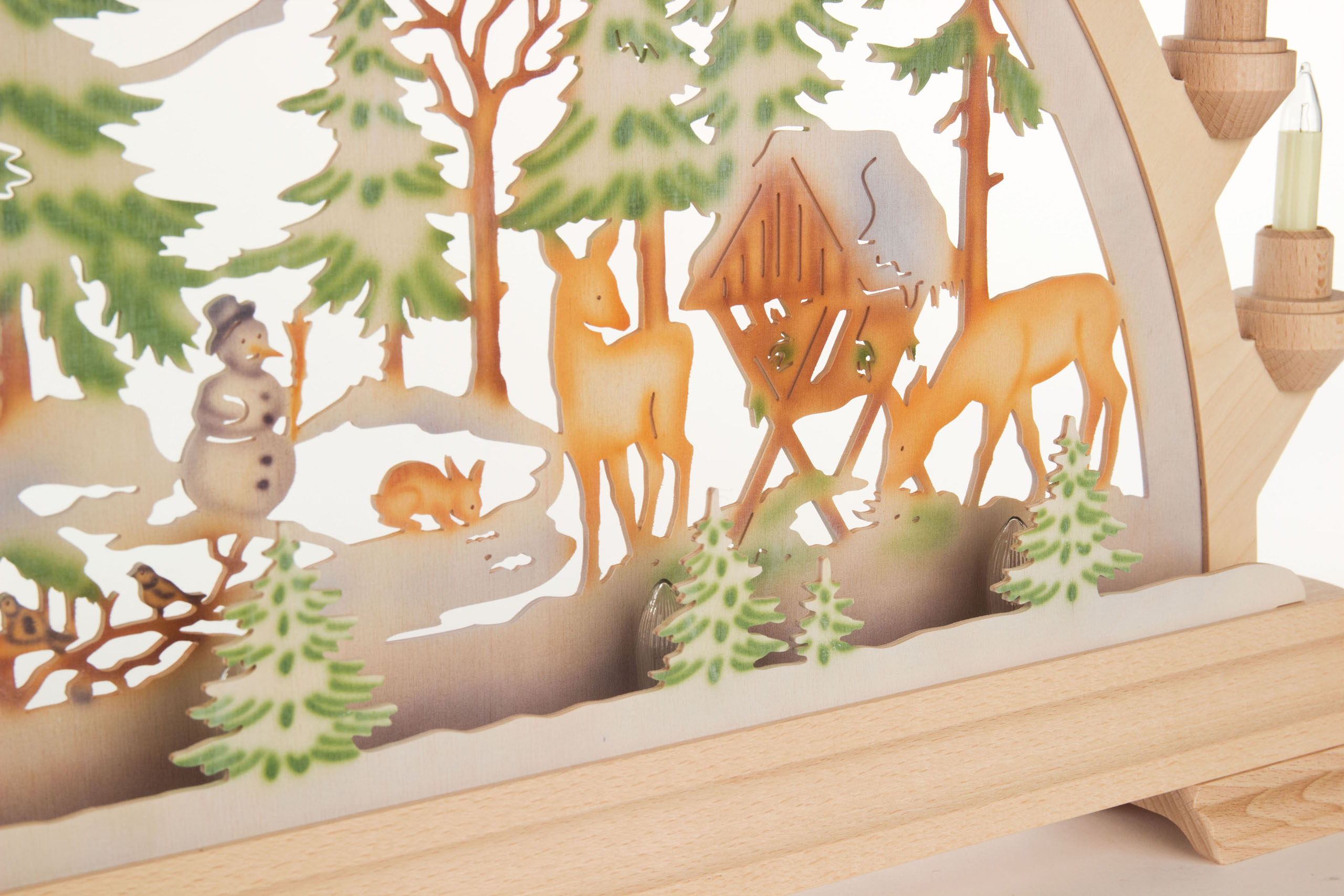 A wooden arch with colorful, electric lighting depicting a forest scene. Features deer, a small wooden house, a snowman, and a rabbit.