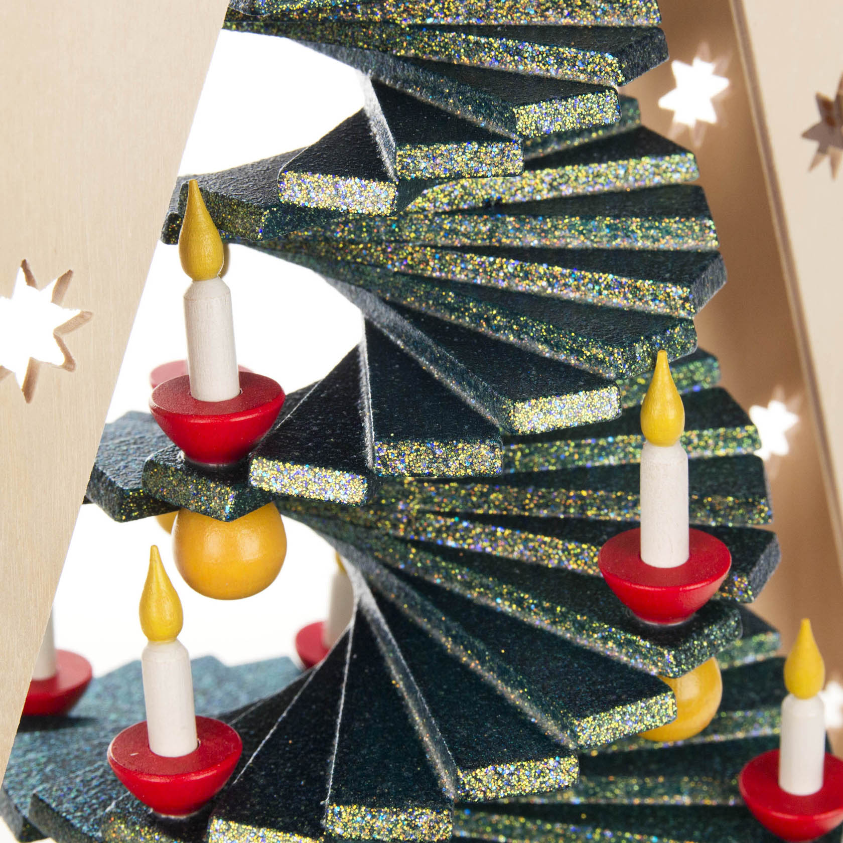 Close-up of a spiral-tiered Christmas tree accentuated with gold glitter, adorned with small red and yellow candle decorations and illuminated by LED lights.