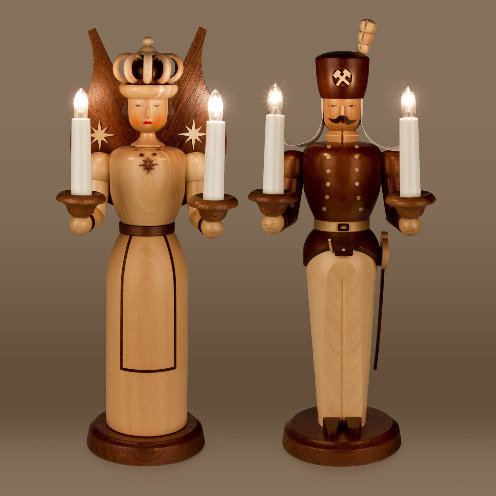 A natural wood angel and miner figurine, each 40cm tall, with electric candles; the angel has a crown and wings, the miner is in uniform with a hat.