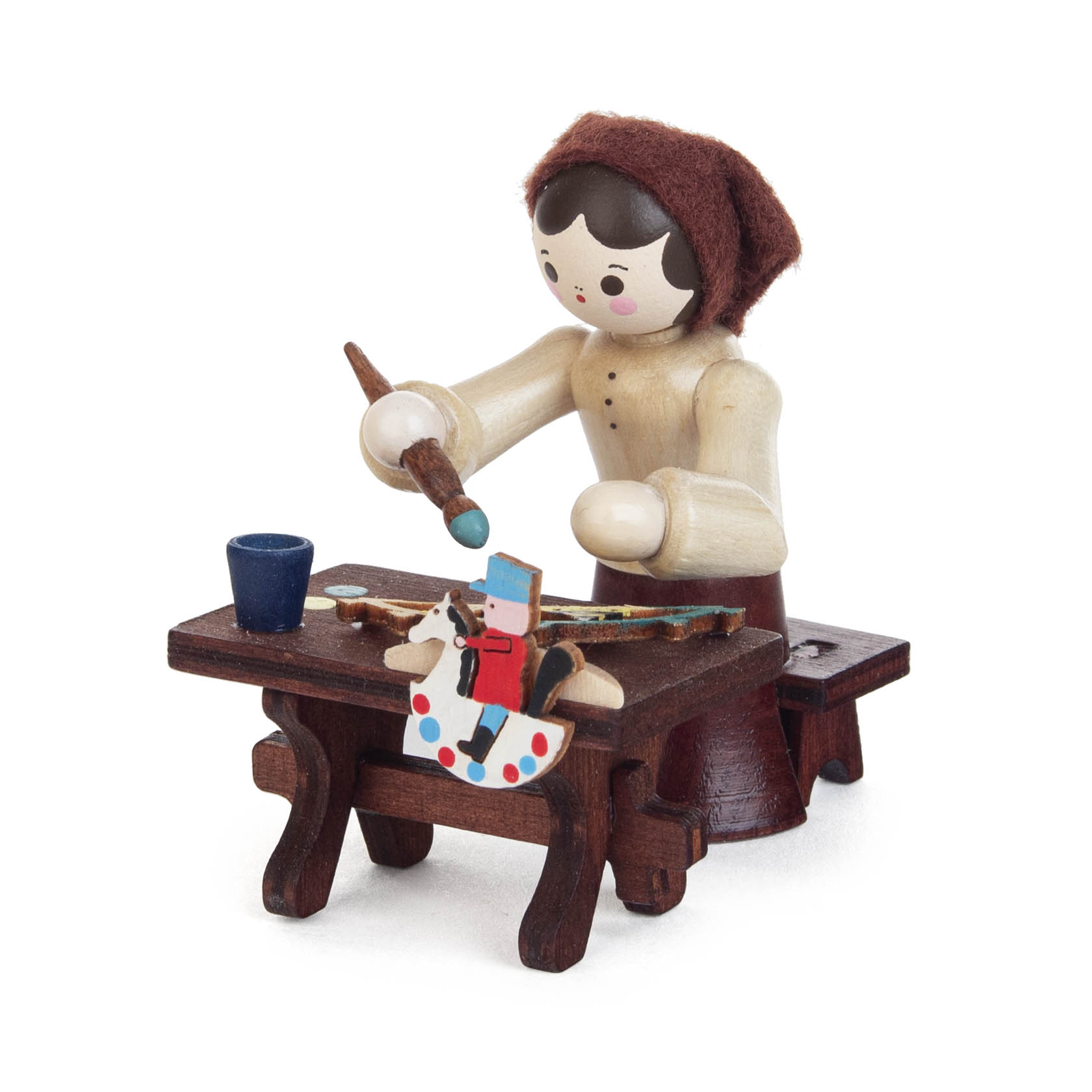 A handcrafted wooden figurine of a female candle holder painter with a red headscarf. She is painting a decorative arch on a wooden table. im Dregeno Online Shop günstig kaufen