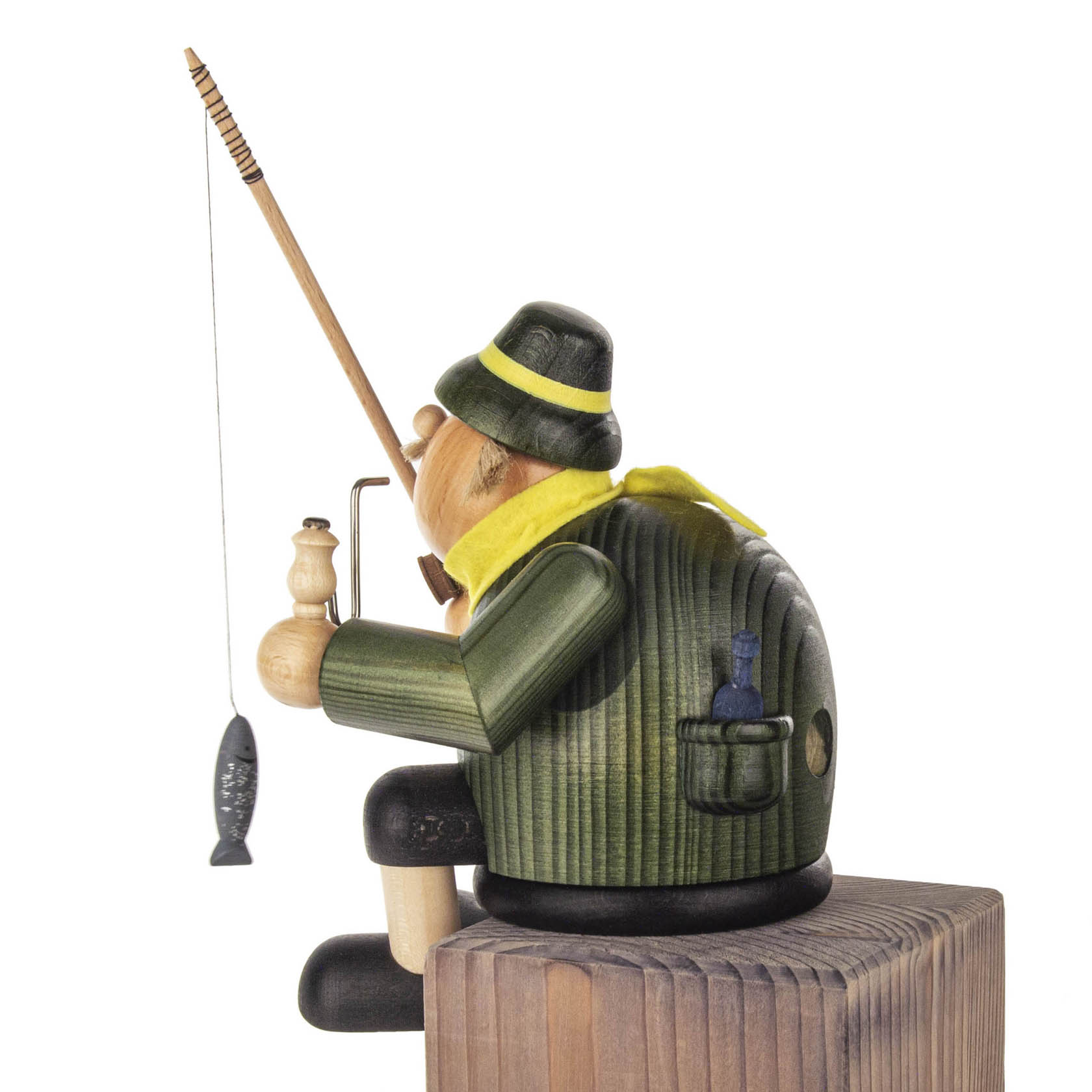 Ein Räuchermann in Form eines Anglers, 18 cm groß, sitzt mit einer Angel auf einem Holzblock. Er trägt einen grünen Hut und Mantel mit einem Fisch in der Angel.
