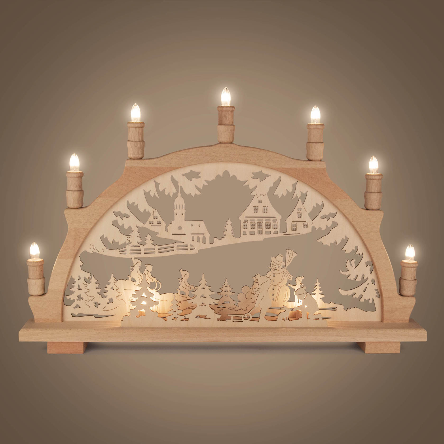 Elektrisch beleuchteter Schwibbogen aus Holz, zeigt eine winterliche Szene mit Kindern, die im Schnee spielen, im Hintergrund eine Kirche und Häuser.