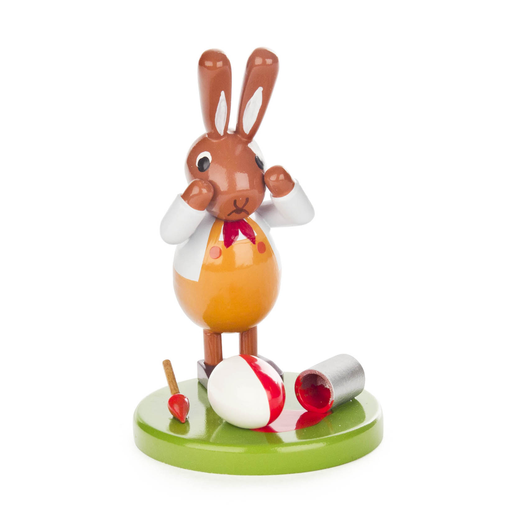 Kleiner dekorativer Hase in Hemd und Krawatte, der einen Farbpinsel hält. Vor ihm ein umgekippter roter Farbeimer und ein Osterei auf grünem Sockel. im Dregeno Online Shop günstig kaufen