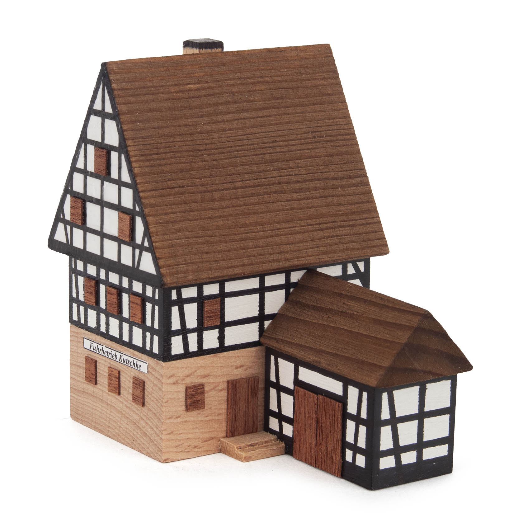 Holzmodell eines Fachwerkhauses mit der Aufschrift 'Fuhrbetrieb Kutschke' am oberen Teil des Erdgeschosses, ergänzt durch einen kleinen Anbau.