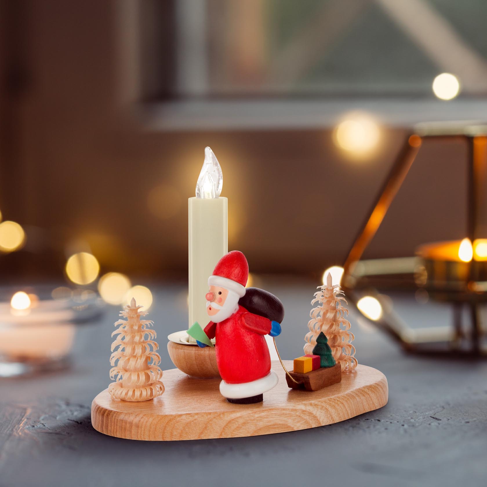 A wooden candle holder featuring a figurine of Saint Nicholas carrying presents, flanked by two small carved trees, with a lit candle.