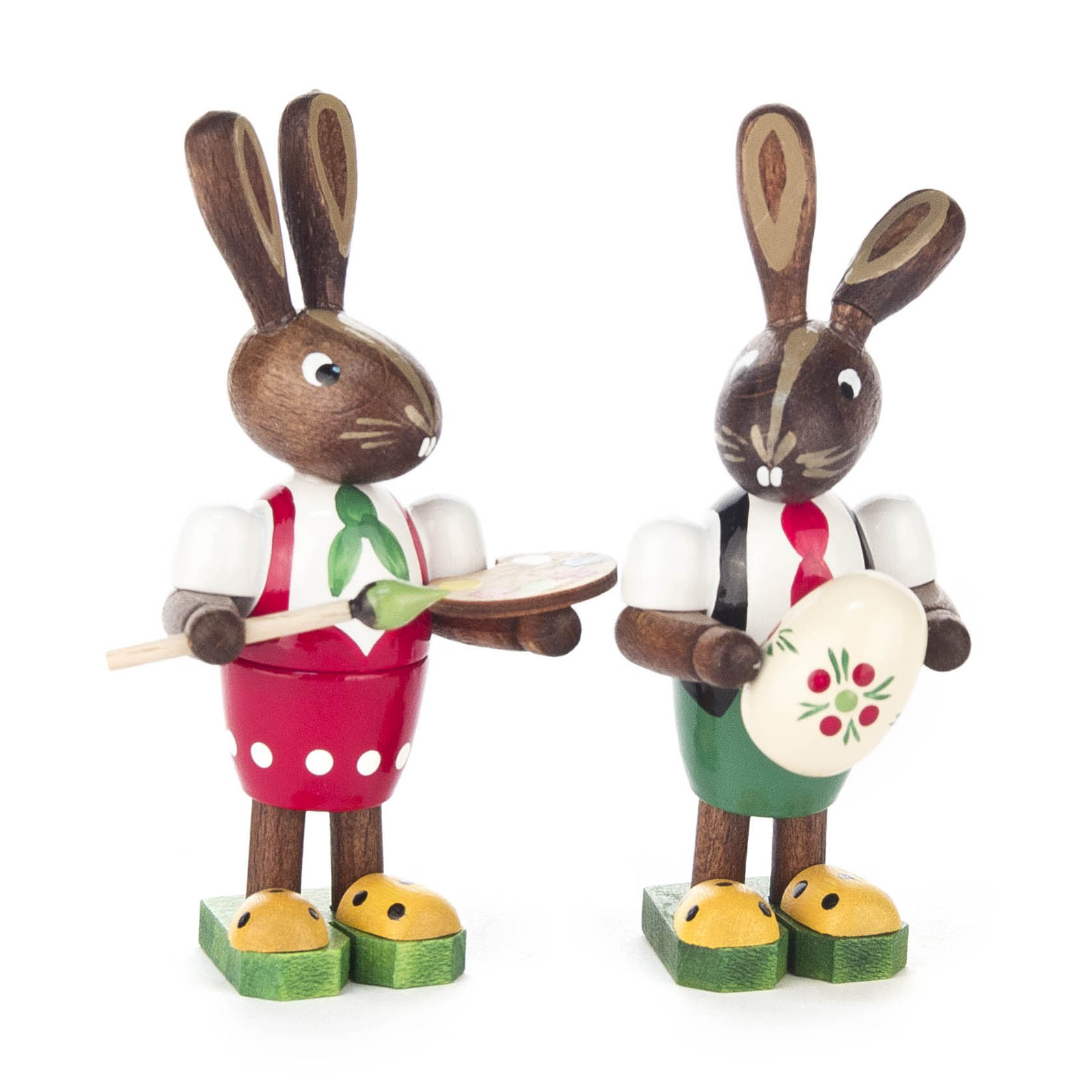 Zwei Holzfiguren von Hasen mit Kleidung. Ein Hase hält eine Palette und Pinsel, der andere ein bemaltes Ei. Beide tragen Schürzen und haben große Ohren. im Dregeno Online Shop günstig kaufen