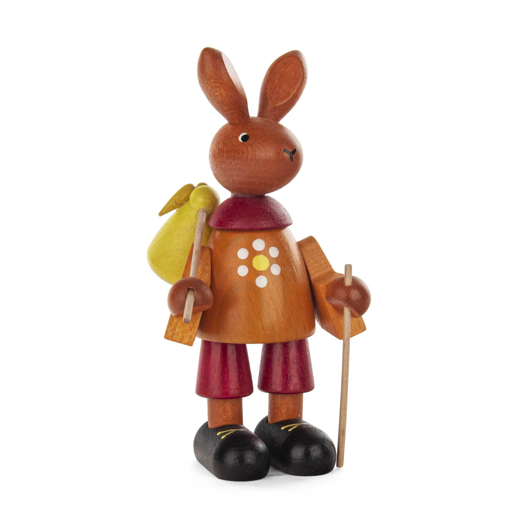 Holzfigur eines Osterhasen, der in einem orangefarbenen Hemd mit weißen Punkten, roten Shorts und schwarzen Schuhen gekleidet ist. Er trägt einen gelben Rucksack und hält einen Wanderstock. im Dregeno Online Shop günstig kaufen