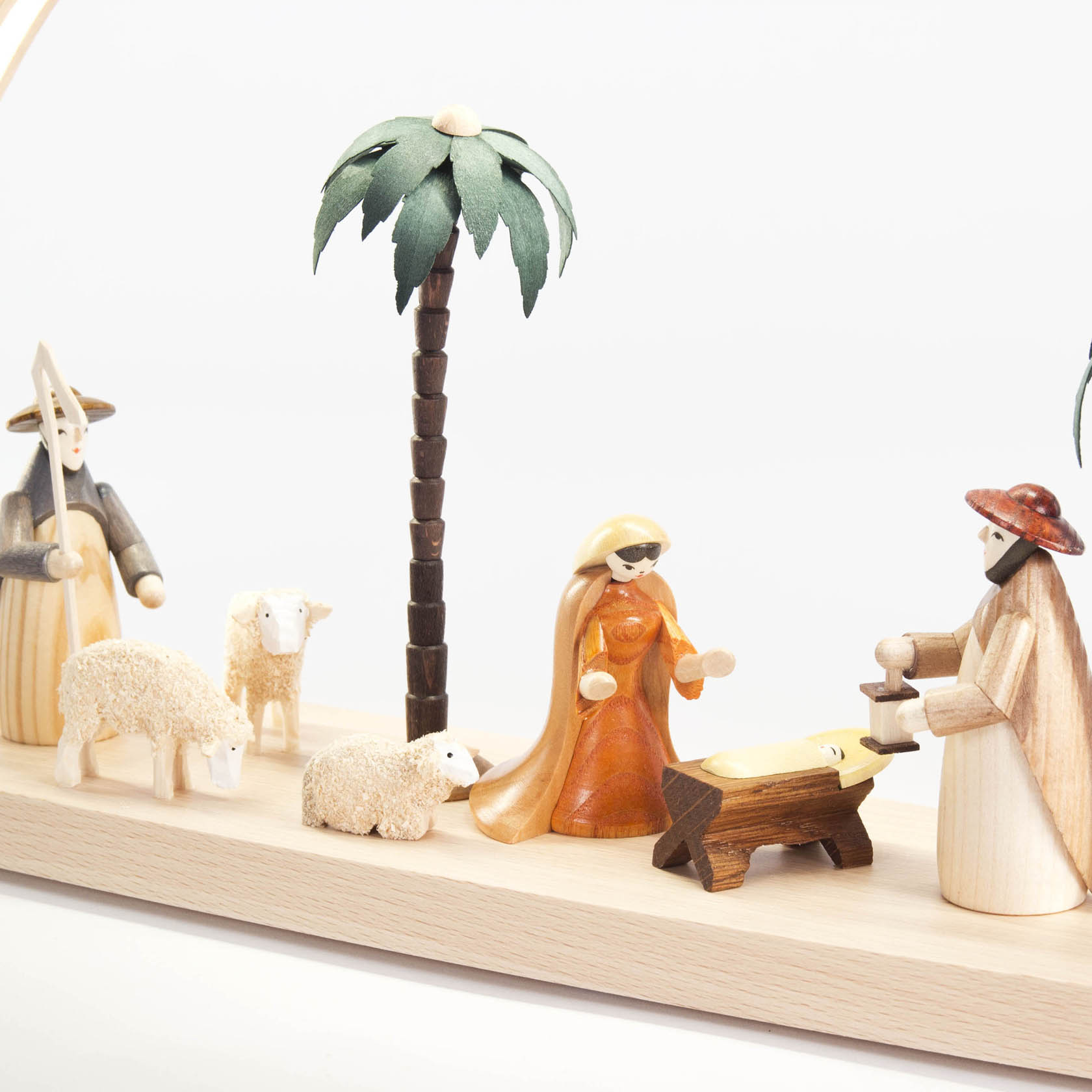 Ein Schwibbogen zeigt die Szene der Geburt Christi. Figuren von Maria, Josef und dem Jesuskind sind sichtbar, flankiert von zwei Schäfchen und einer Palme.