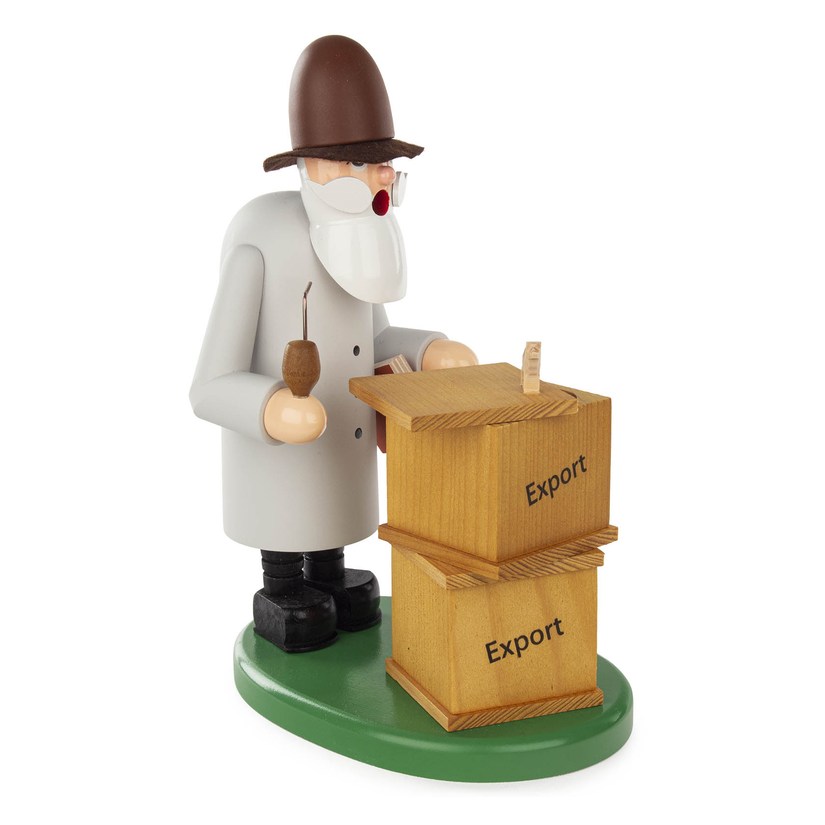 Ein handgefertigter Räuchermann in der Rolle eines Verlegers. Er trägt einen braunen Hut, grauen Mantel, hält eine Pfeife und steht neben zwei Kisten mit 'Export' Aufschrift.