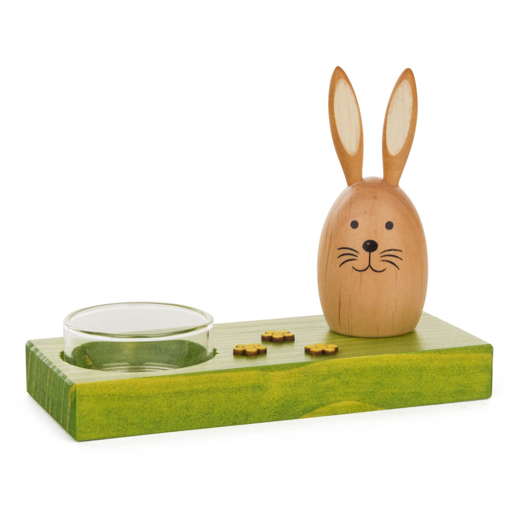 Ein Holz-Teelichthalter mit einem Hasen. Der Hasenkopf ist eiförmig und naturholzfarben, mit aufgemaltem Gesicht und langen Ohren, auf einem grünen Sockel montiert. im Dregeno Online Shop günstig kaufen