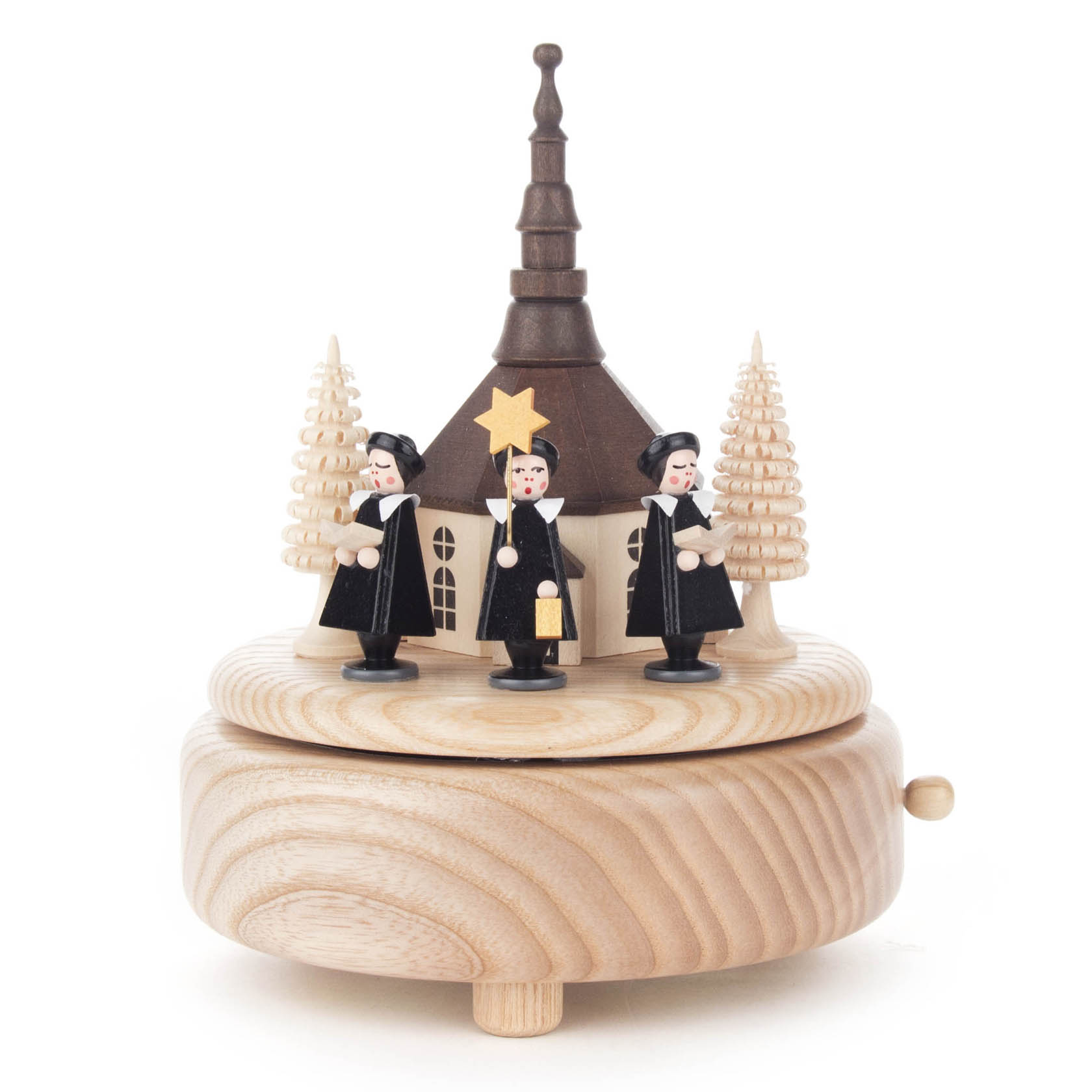 Spieldose aus Holz mit der Seiffener Kirche und drei schwarzen Kurrendefiguren, die ein Lied singen. Im Hintergrund sind zwei geschnitzte Tannenbäume sichtbar. im Dregeno Online Shop günstig kaufen