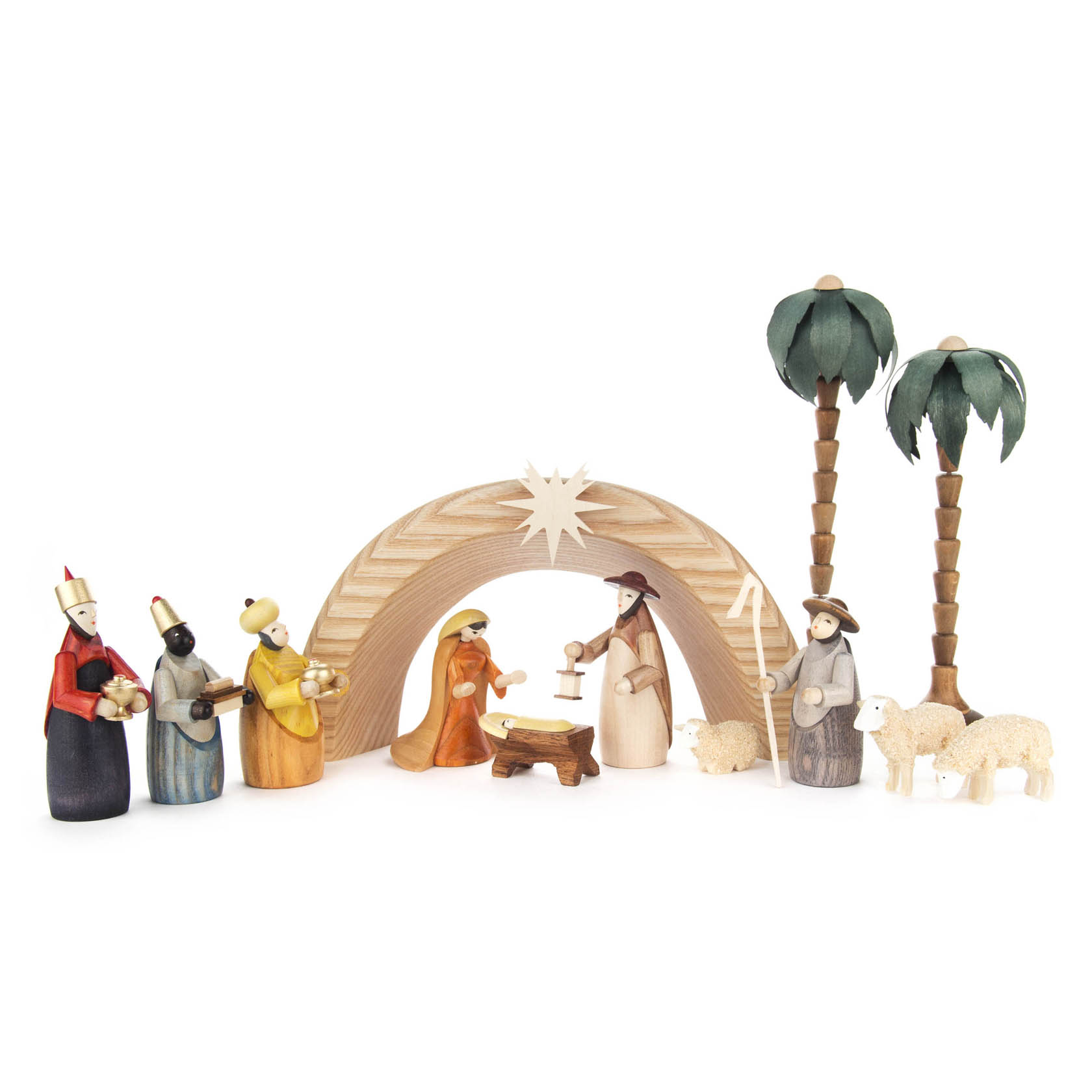 Handgefertigte, farbige Krippenfiguren aus Holz stehen um eine Krippe mit einem Bogen und zwei Palmen. Zu sehen sind Maria, Josef, Jesuskind, ein Schaf und drei Könige. im Dregeno Online Shop günstig kaufen