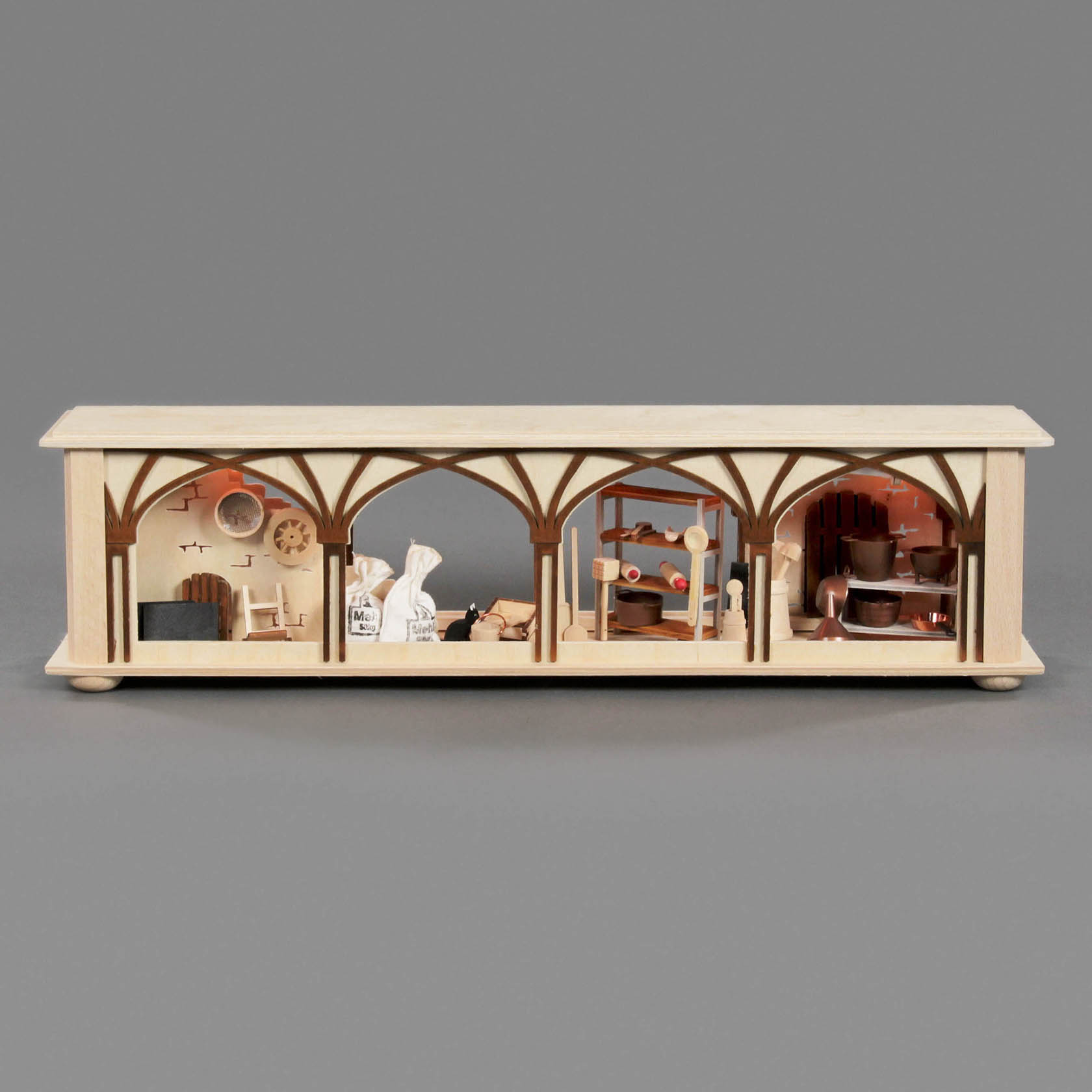 Ein miniaturisiertes, elektrisch beleuchtetes Holzmodell mit drei Räumen: einer mit Mehlsäcken, einer mit verschiedenen Utensilien und einer mit entworfenen Elementen.