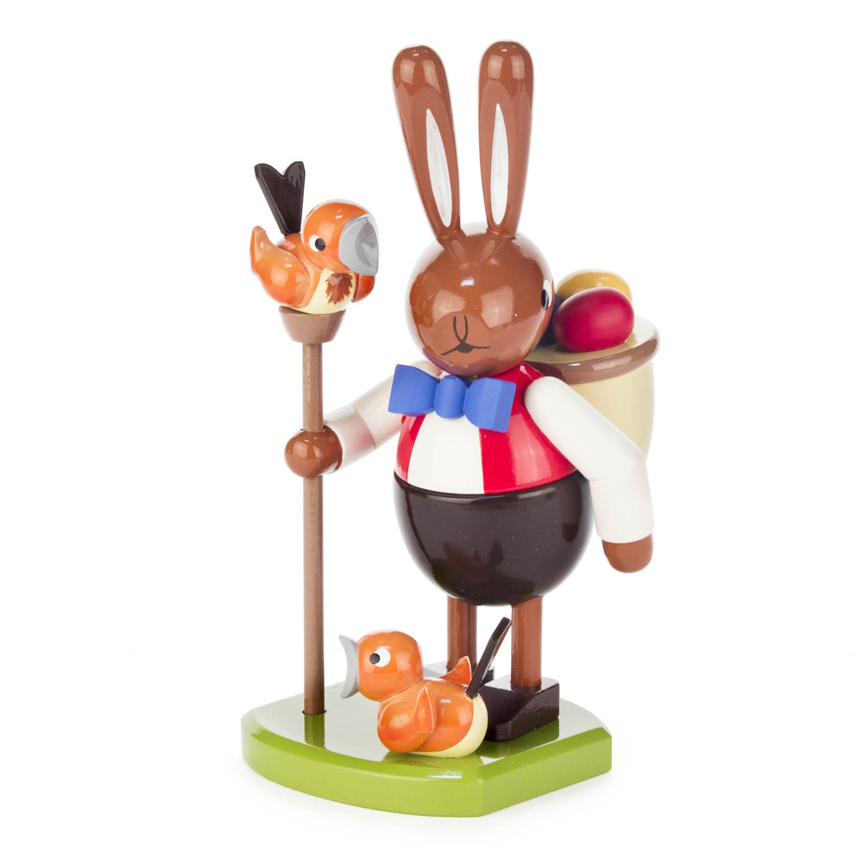Holzfigur eines Hasen in einer roten Weste mit blauer Fliege, der einen Wanderstock mit einem kleinen Vogel hält und einen Rucksack mit bunten Ostereiern trägt. im Dregeno Online Shop günstig kaufen