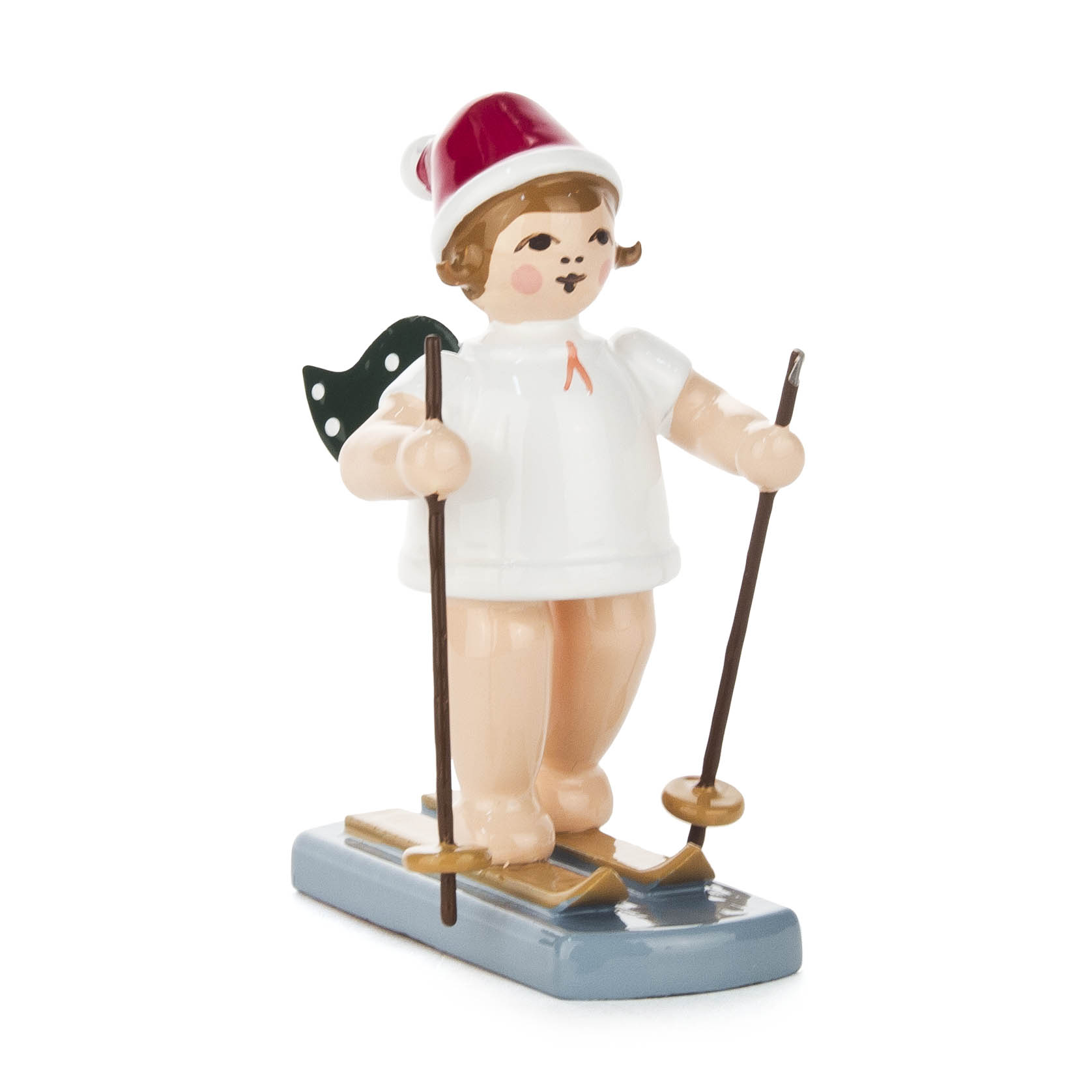 Eine Holzfigur eines Engels mit grün gepunkteten Flügeln in einem weißen Kleid, roter Mütze, auf Skiern stehend, mit Skistöcken in der Hand. im Dregeno Online Shop günstig kaufen