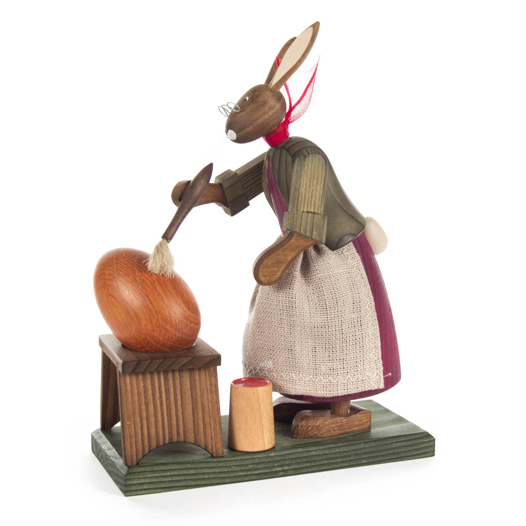Holzfigur einer Hasen-Großmutter mit Brille, die ein großes Ei bemalt. Sie trägt eine Schürze und hat einen Pinsel in der Tatze. im Dregeno Online Shop günstig kaufen