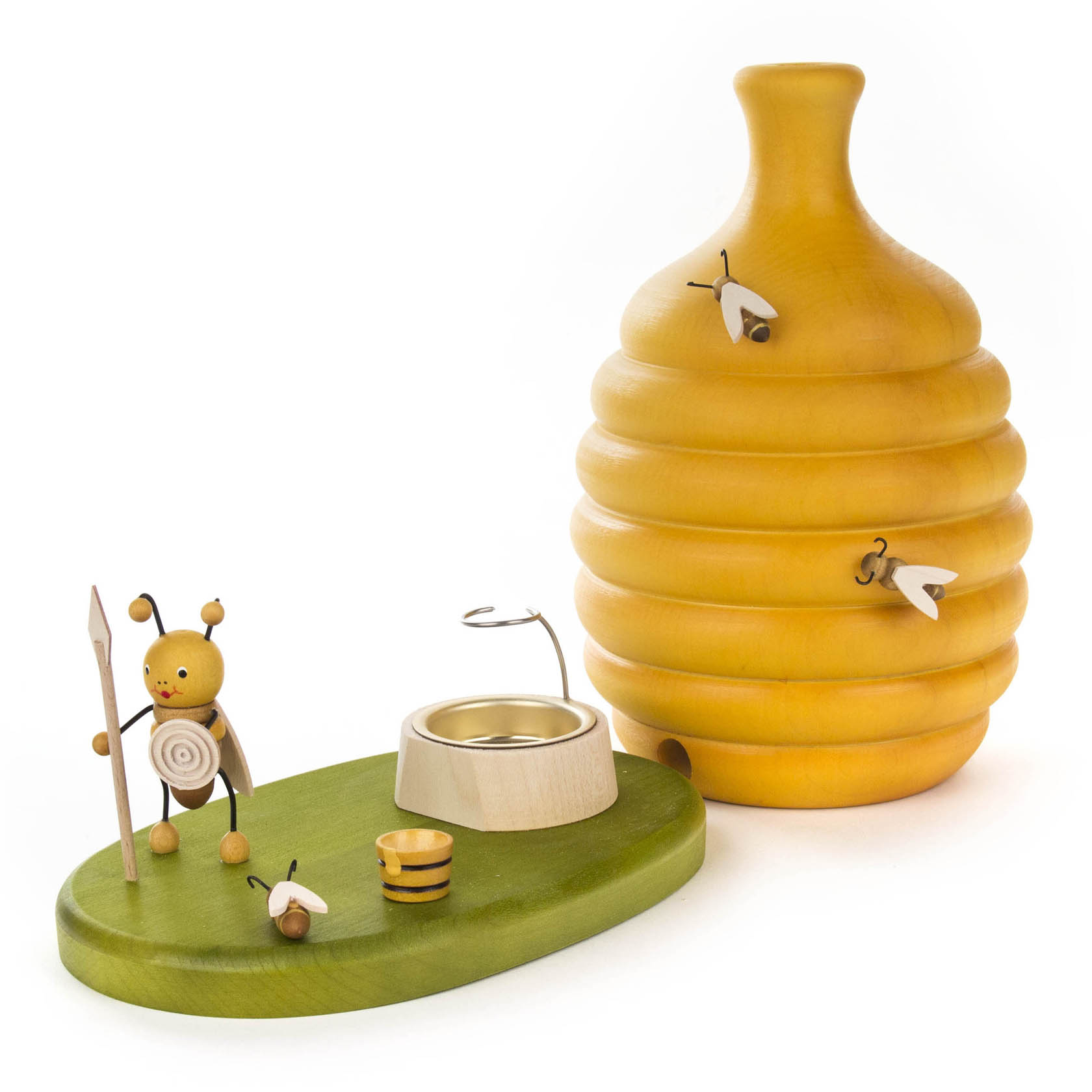 Großer gelber Bienenstock aus Holz mit Räucherfunktion, begleitet von einer kleinen, hölzernen Bienenfigur mit Speer und einem kleinen Eimer.