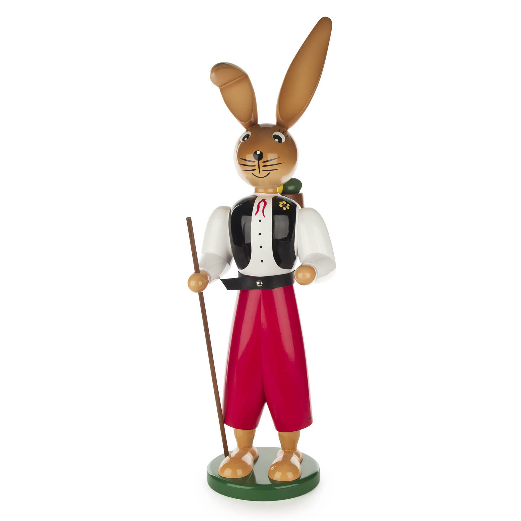 Holzfigur eines Hasenwanderburschen mit roter Hose, weißem Hemd, schwarzer Weste und Wanderstock. Der Hase hat lange Ohren und steht auf einem grünen Sockel. im Dregeno Online Shop günstig kaufen