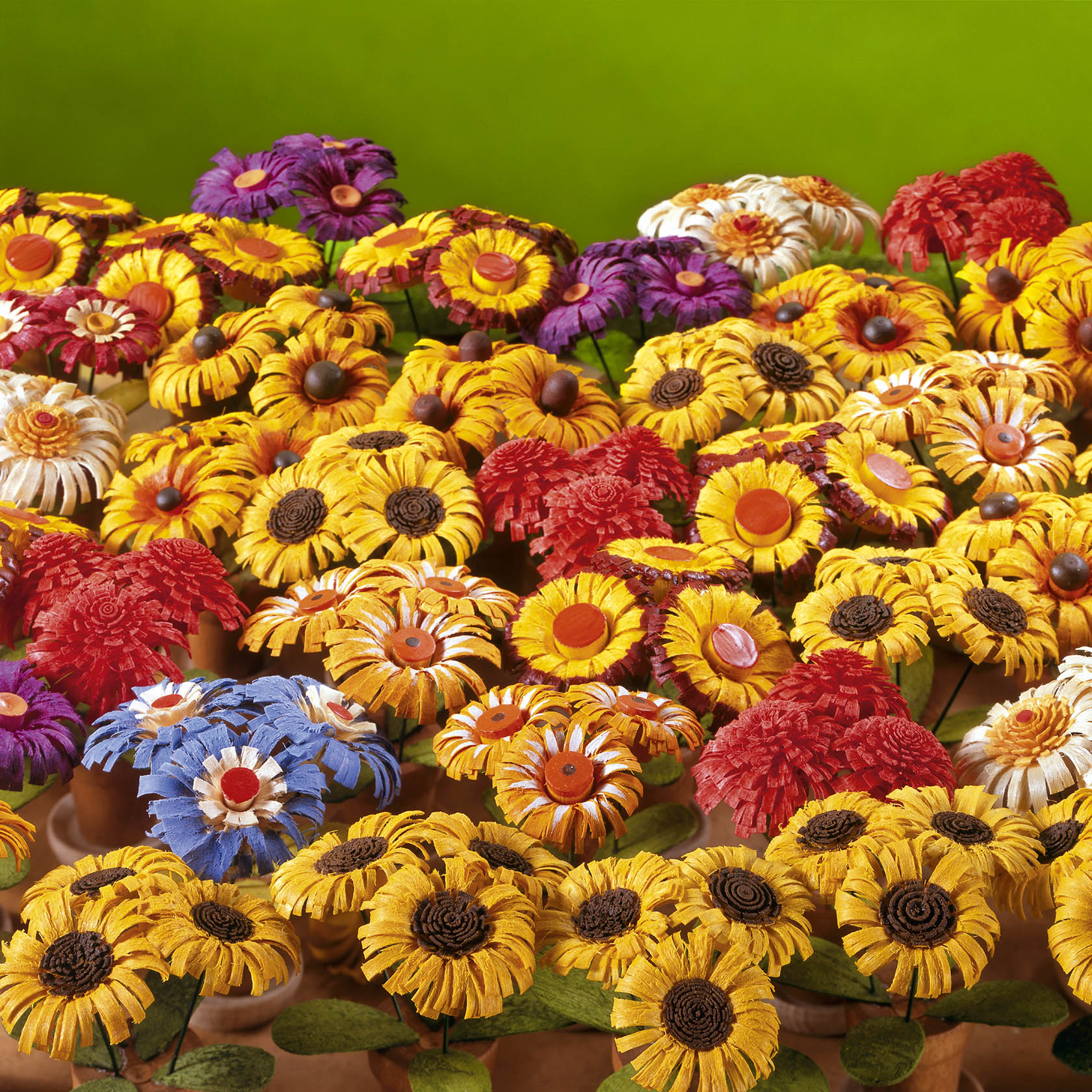 Ein Arrangement aus zahlreichen leuchtend gefärbten künstlichen Blüten in verschiedenen Farben wie Gelb, Rot, Blau und Lila.