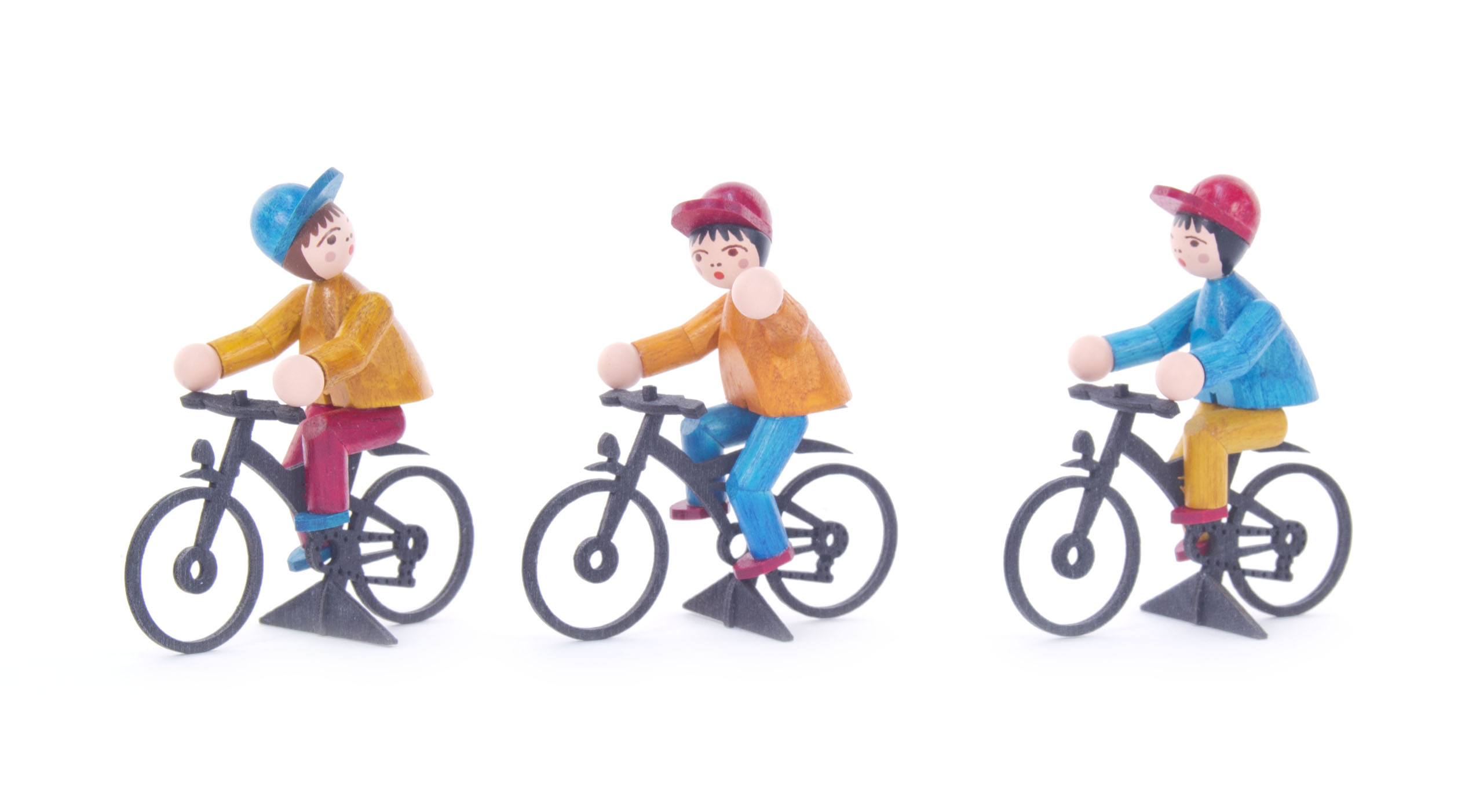 Drei farbig lasierte Holzfiguren von Fahrradfahrern, jede trägt eine Mütze und bunte Kleidung. Sie sitzen jeweils auf einem schwarzen Fahrrad.