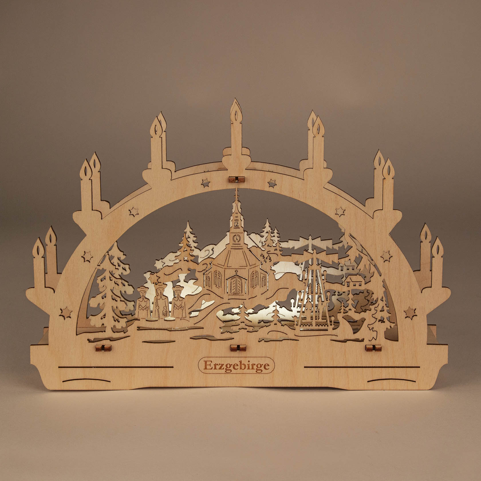 Ein Schwibbogen mit Motiv der Seiffener Kirche, LED-beleuchtet, aus hellem Holz gefertigt, mit fensterartigen Ausschnitten des Kirchenmotivs.