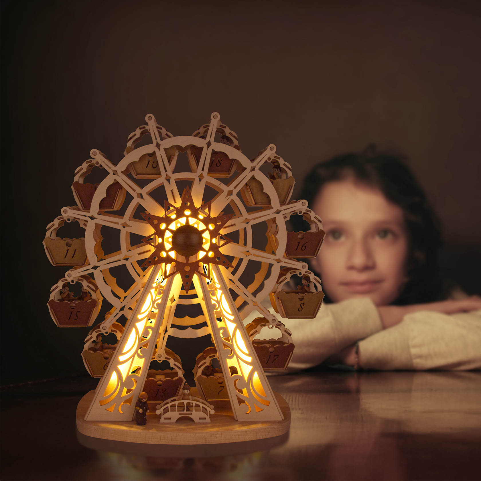 Kind betrachtet ein leuchtendes Modell eines Riesenrads mit Adventskalender, das doppelte Gondeln und LED-Beleuchtung hat.