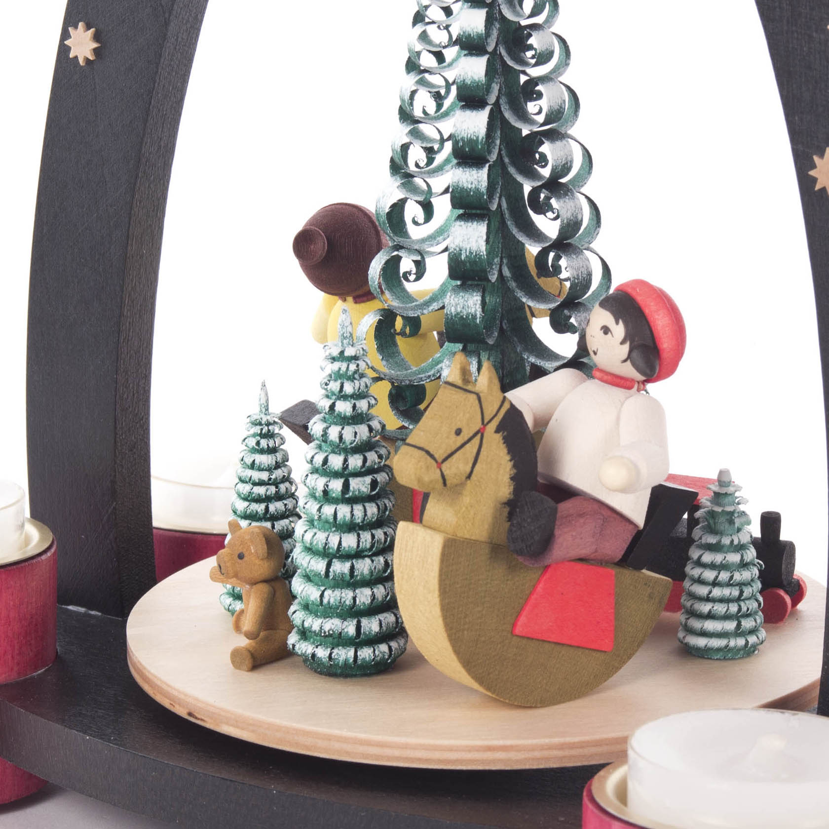 Holzpyramide mit einer Szene, die Kinder auf Schaukelpferden, grüne Bäume und einen Teddybär zeigt. Die Pyramide ist für Teelichter gestaltet.
