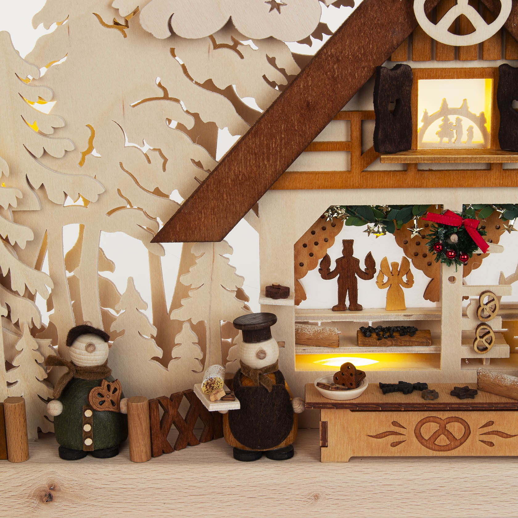 A wooden candle arch scene depicting a small bakery with figurines and baked goods, illuminated indirectly by electric light.