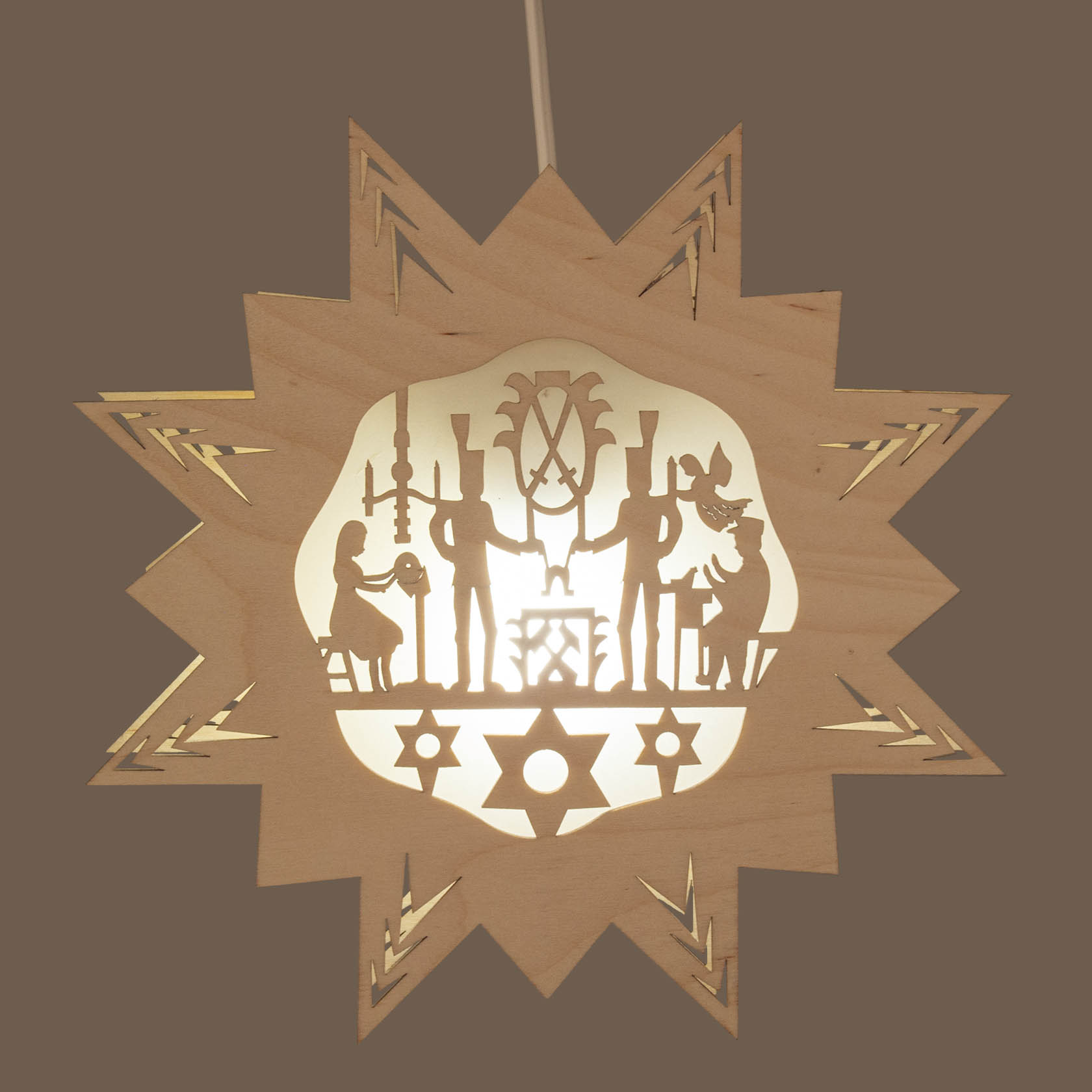 Holzstern mit filigranen Figuren und Szenen aus dem Erzgebirge, beleuchtet von elektrischer Beleuchtung, auf Papier hinterlegt.