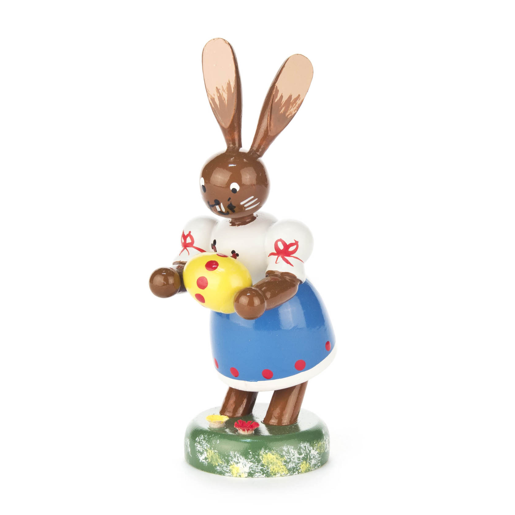 Holzfigur einer stehenden Häsin mit blauer Schürze und weißer Bluse, die ein gelbes Osterei mit roten Punkten hält. im Dregeno Online Shop günstig kaufen