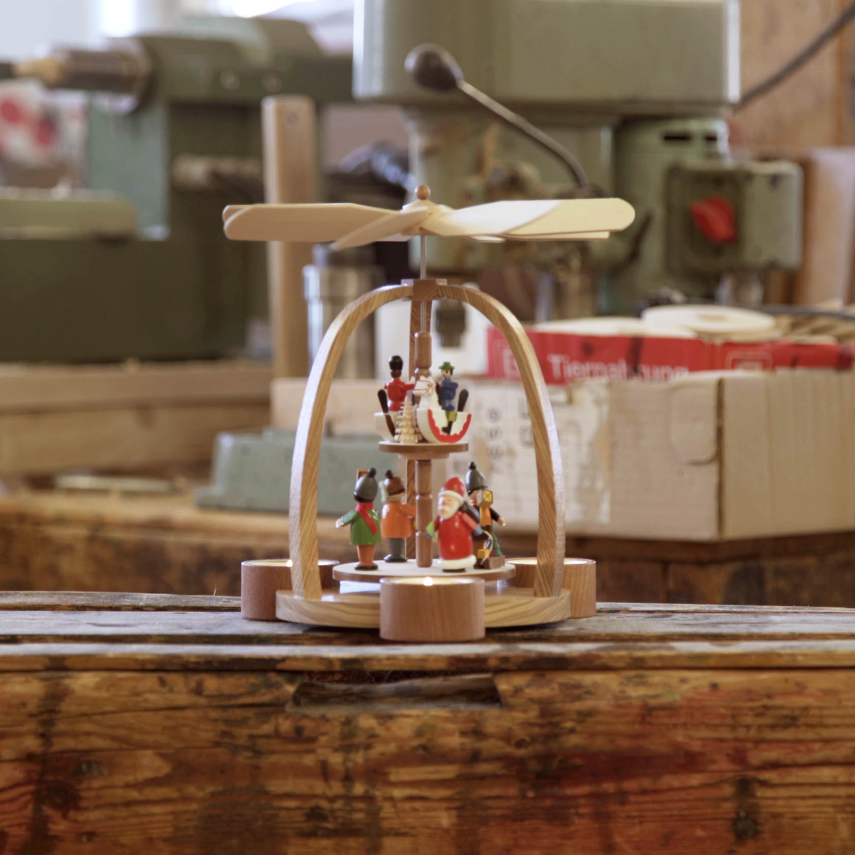 Holzpyramide mit zwei Ebenen, oben Figuren eines Reiters und unten eines Weihnachtsmanns, angetrieben durch Teelichter, mit sich drehendem Rotor.