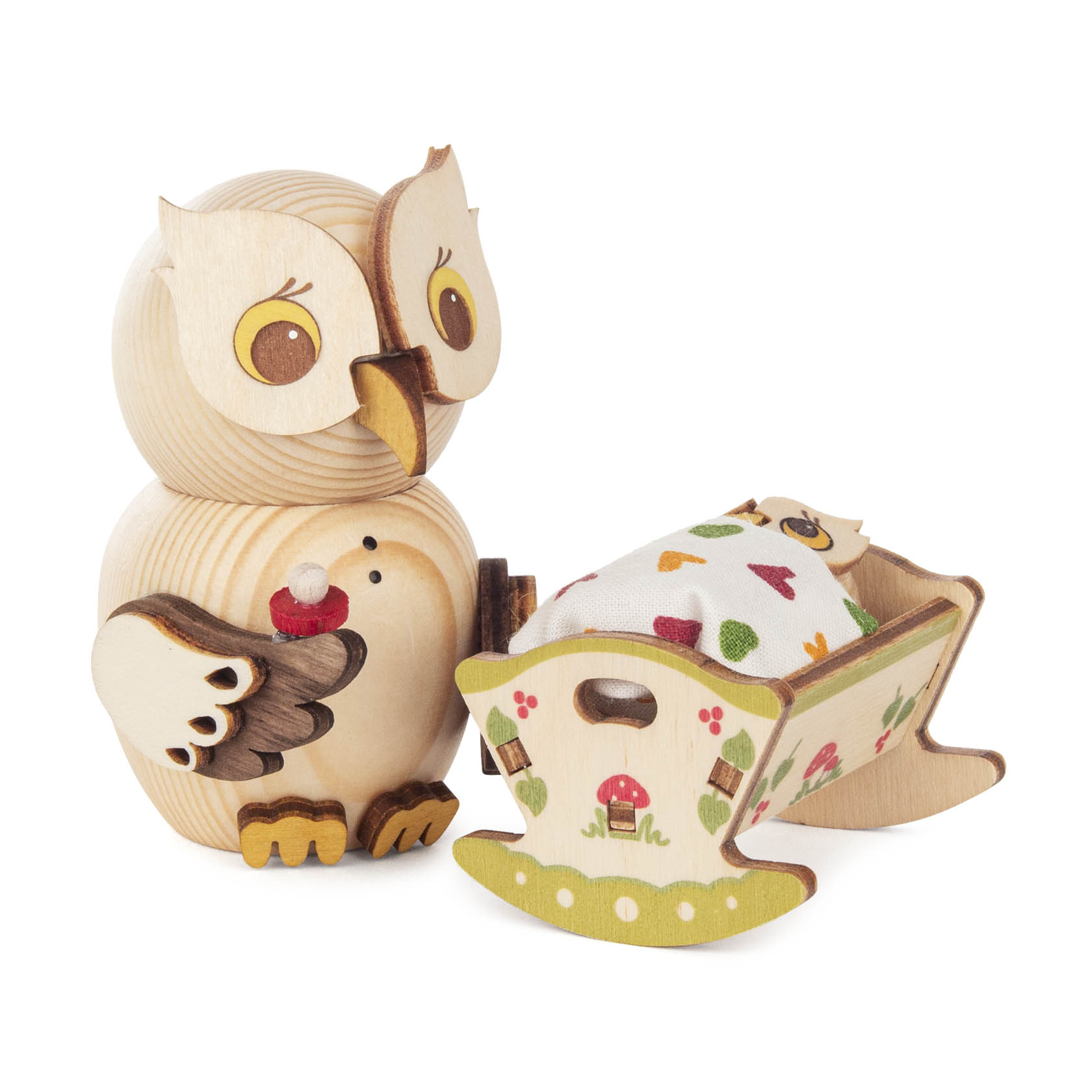 Niedliche Holzfigur einer kleinen Eule, die einen roten Apfel hält, steht neben einer dekorativen Babywiege mit gemustertem Tuch. im Dregeno Online Shop günstig kaufen