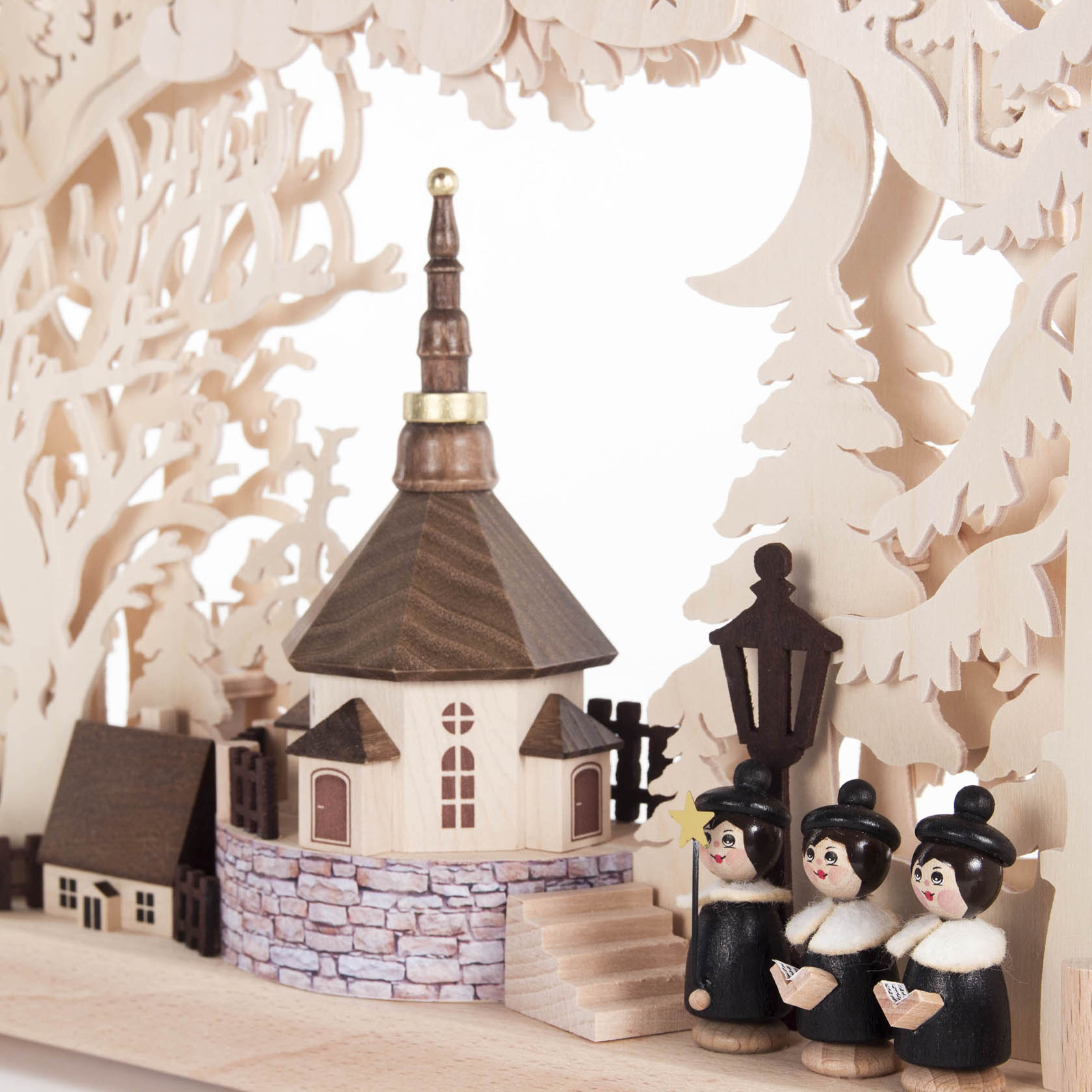 A small Schwibbogen with an indirect electric light featuring a wooden model of a village church with a steeple and three wooden carolers.