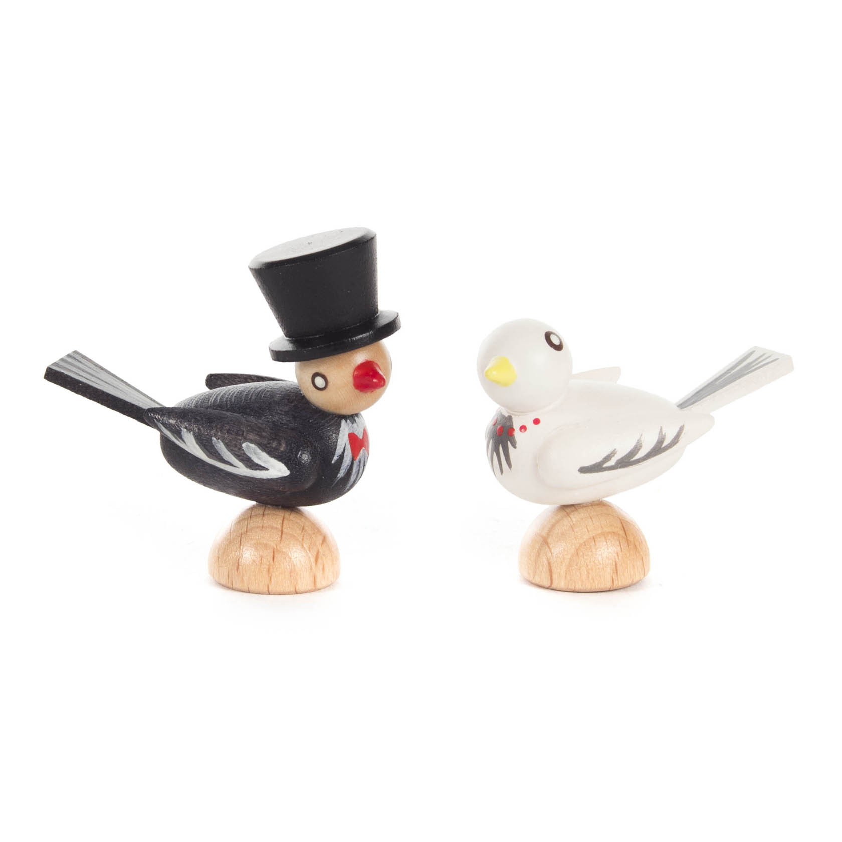 Zwei hölzerne Vogelfiguren auf Holzsockeln. Ein schwarzer Vogel mit Zylinder und rotem Schnabel, ein weißer Vogel mit gelbem Schnabel. im Dregeno Online Shop günstig kaufen