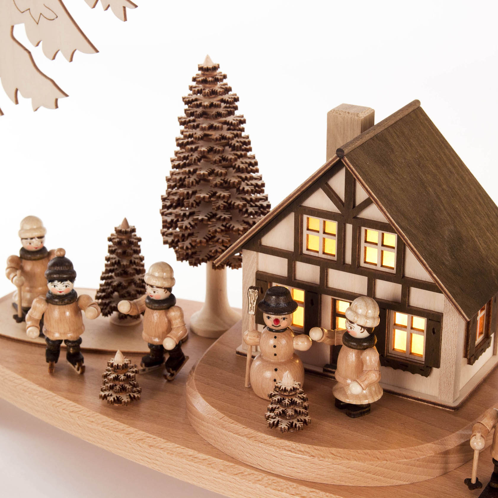 Elektrisch beleuchteter Schwibbogen mit einem Haus und Winterkindern, umgeben von Bäumen. Kinder und Schneemann in Winterkleidung.