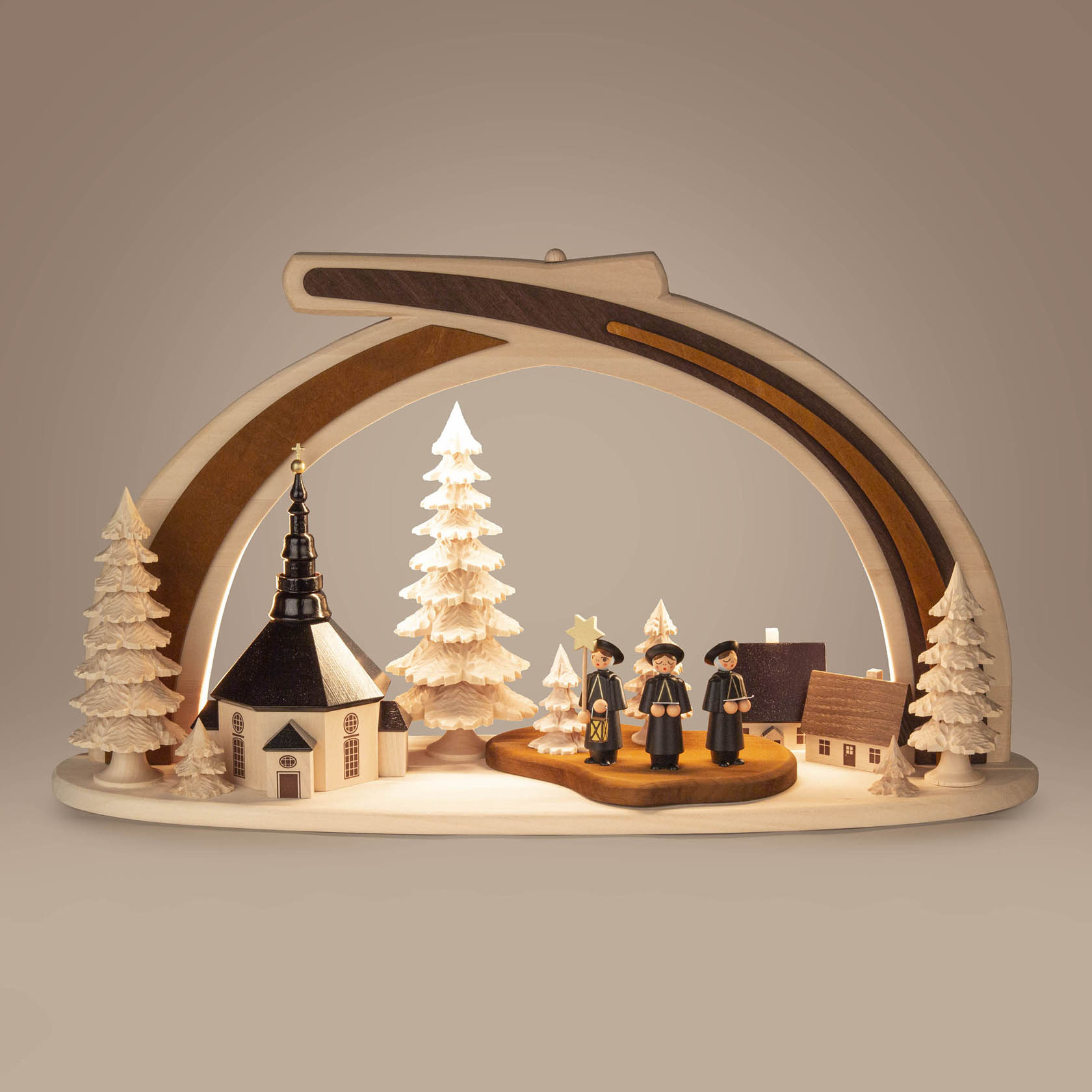 Ein Massivholzbogen zeigt eine Seiffener Kirche, flankiert von drei Bäumen und drei Kurrende-Figuren mit LED-Beleuchtung.