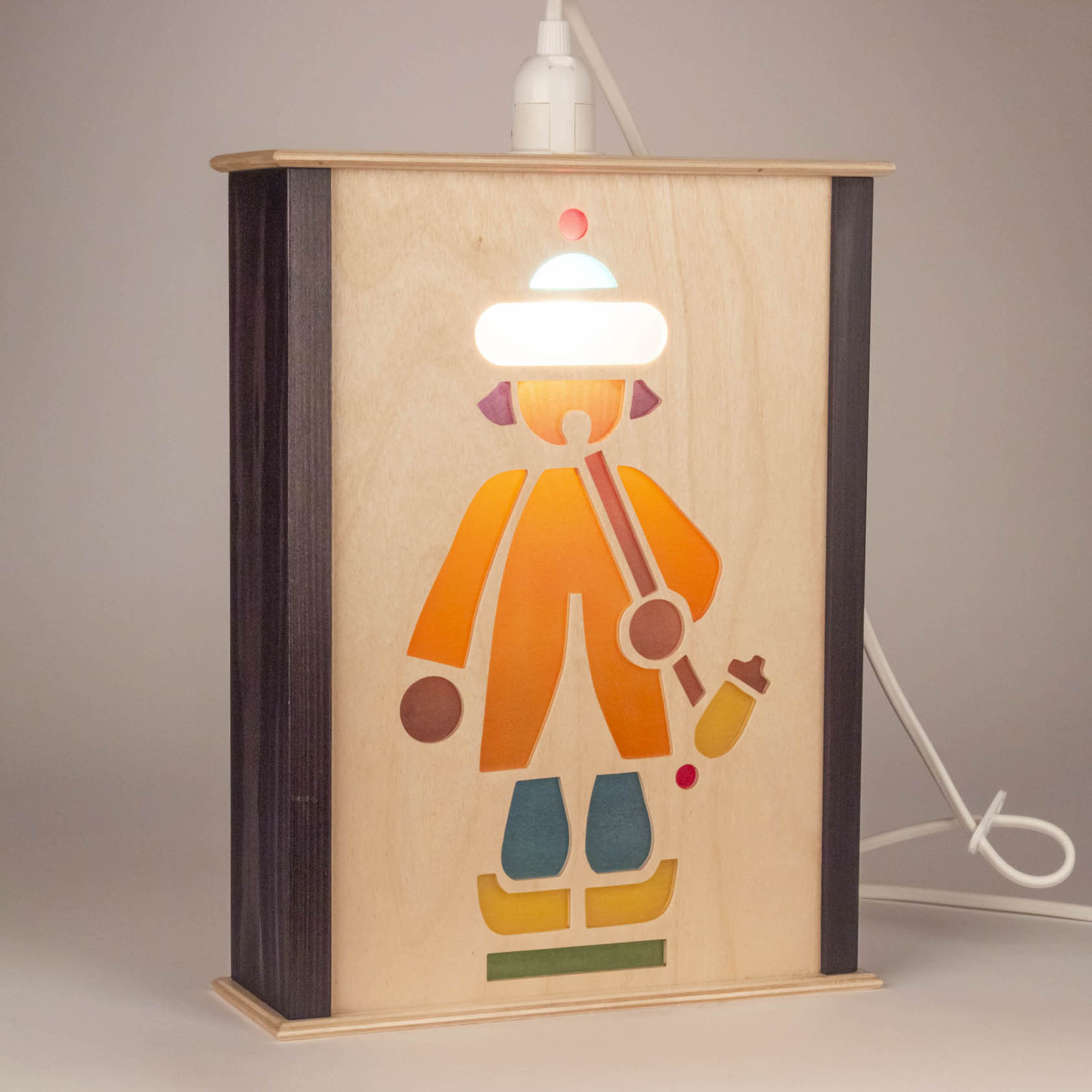Holzlaterne mit ausgeschnittenem, stilisiertem Motiv eines Reiters in bunter Kleidung und heller Mütze. Das innere Licht beleuchtet das Motiv von hinten.