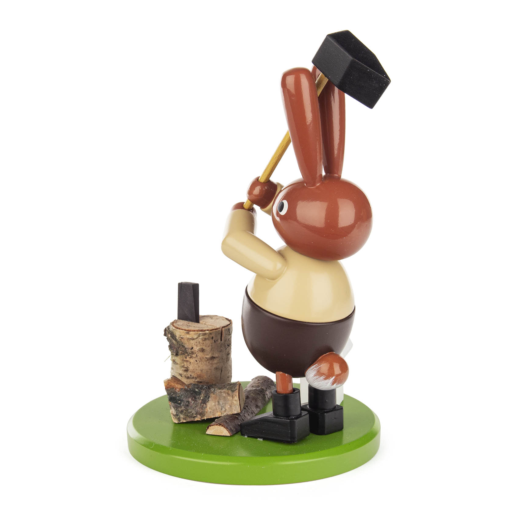 Eine hölzerne Hasenfigur steht auf einem grünen Sockel und ist dabei, Holz mit einem Hammer zu spalten. Der Hase hat braunes Fell und eine gelbe Bekleidung.