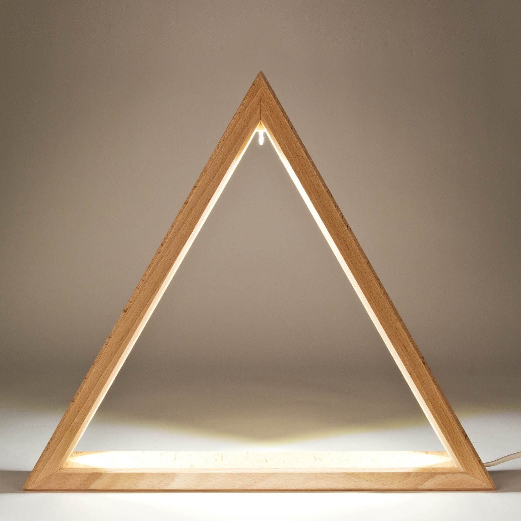 Holzdreieck-Lampe mit LED-Beleuchtung, steht auf einer flachen Fläche. Das Licht strahlt von innen und erzeugt eine warme Atmosphäre.