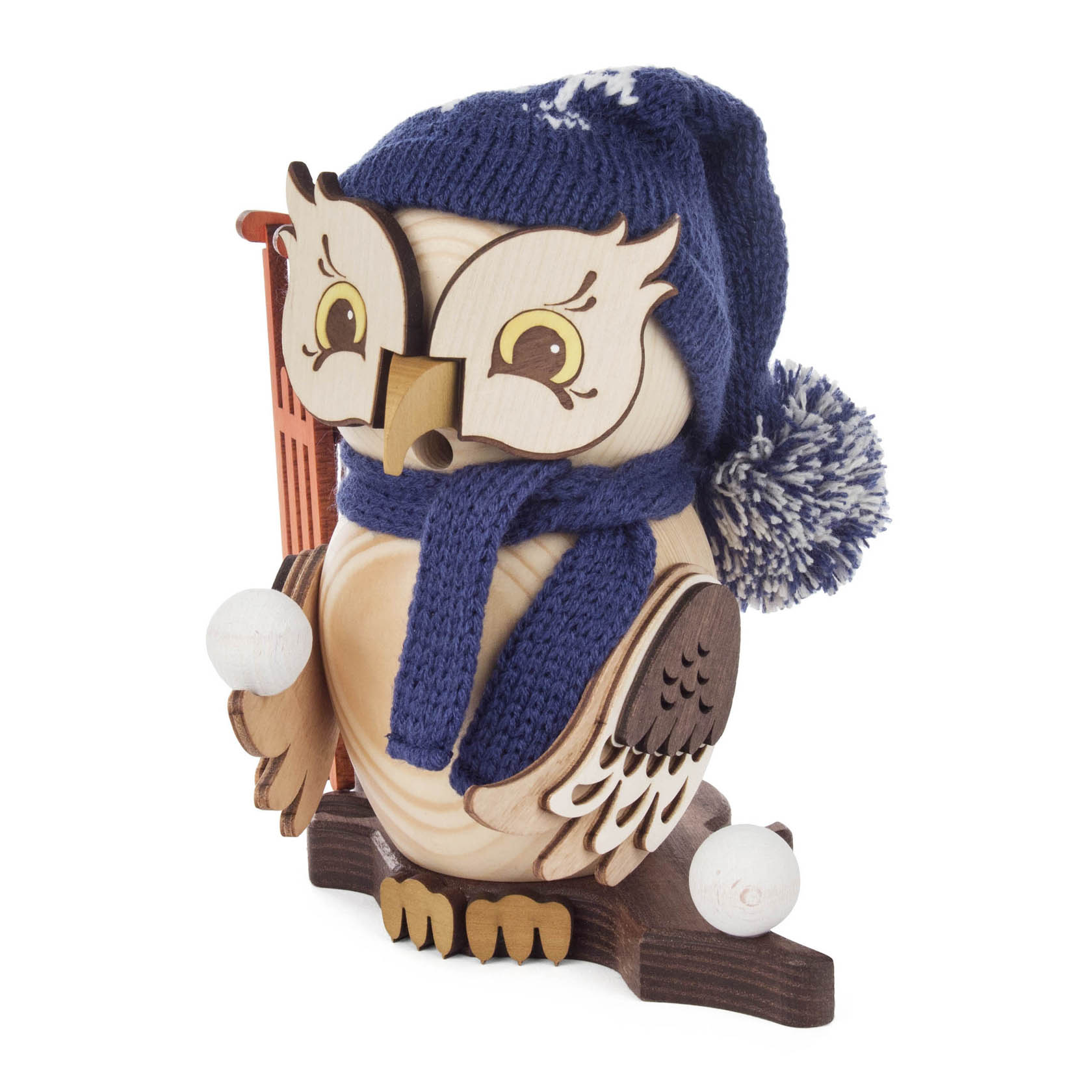 Holzeule mit blauer Wollmütze und Schal hält einen Schlitten. Sie bläst Rauch aus ihrem Schnabel und steht auf einem Holzsockel.