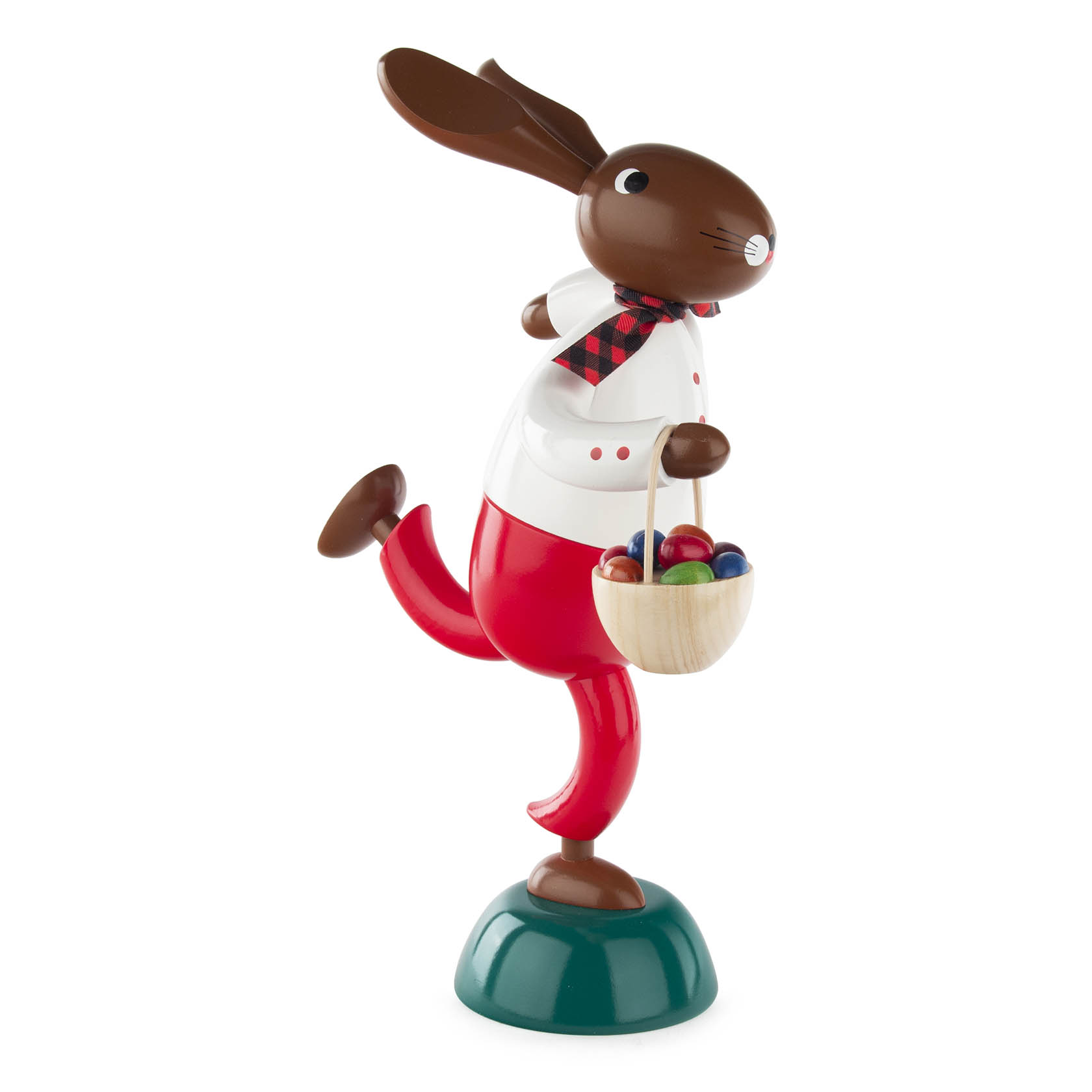 Eine große Hasenfigur in roter Hose und weißem Hemd mit schwarz-rotem Schal. Der Hase hält einen Korb mit bunten Eiern und steht auf einem Bein. im Dregeno Online Shop günstig kaufen