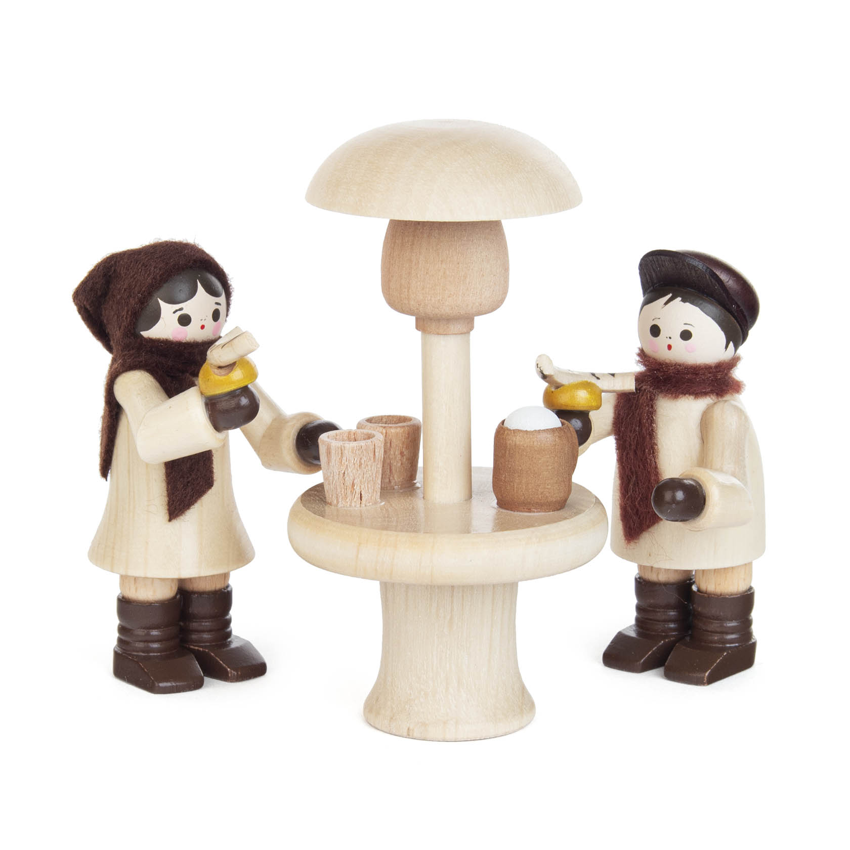 Two wooden figurines dressed in winter clothes enjoying drinks around a high round table with an overhead heater.