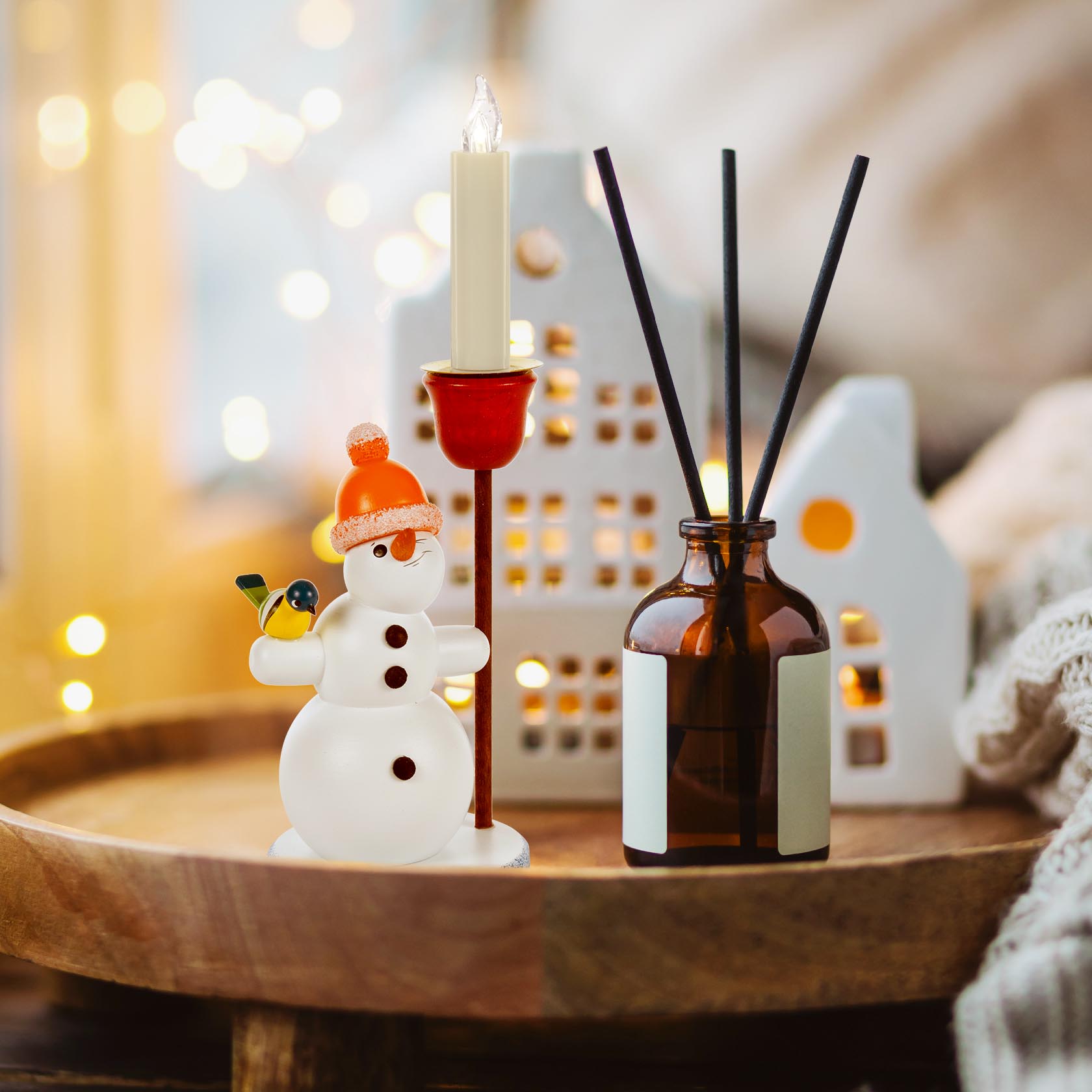 Kleiner Schneemann aus Glas mit orangener Pudelmütze, hält einen Kerzenhalter für eine 14mm Kerze in der Hand.