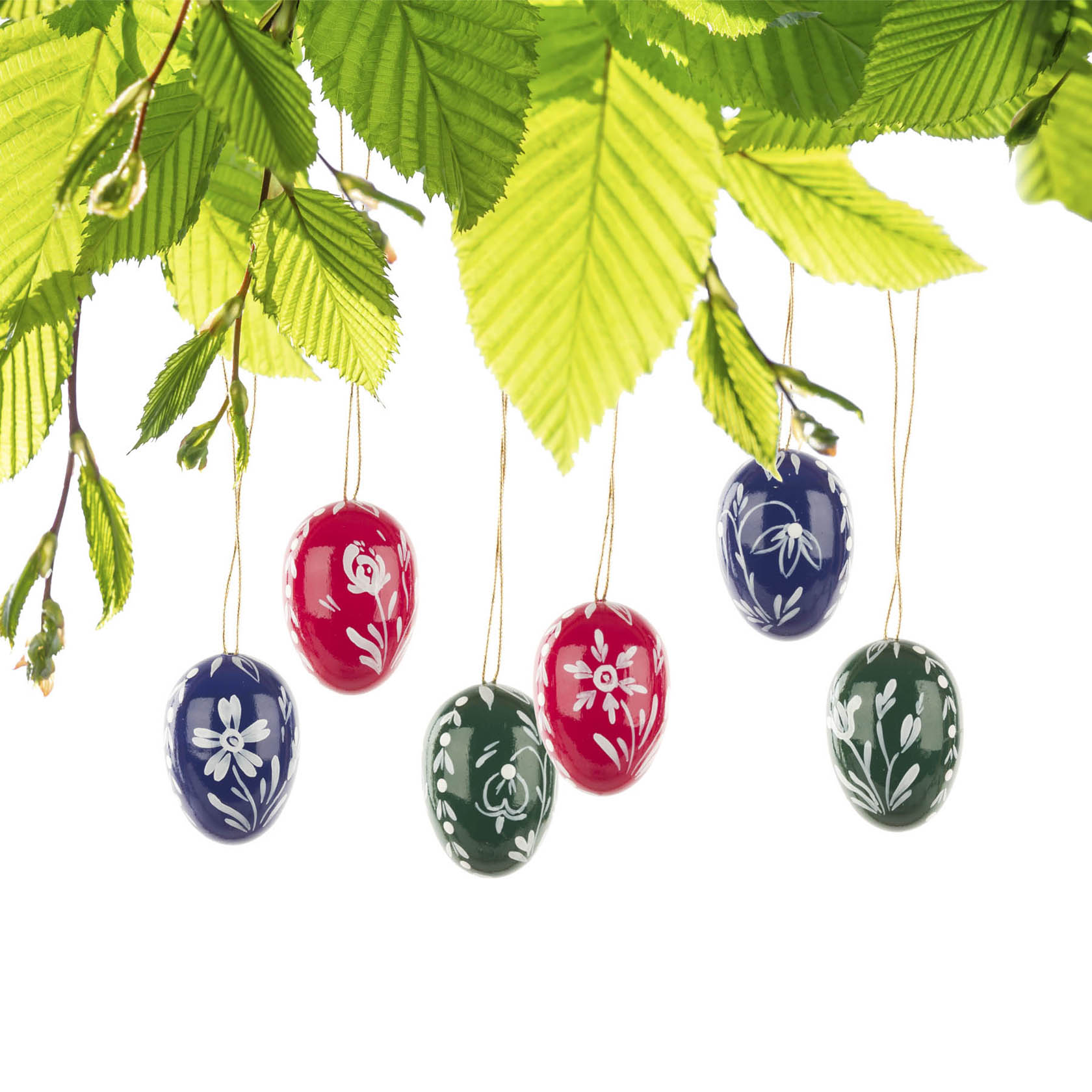 Sechs handbemalte Ostereier in Rot, Blau und Grün, verziert mit weißen Blumenmustern, hängen an dünnen Fäden vor grünem Laub.