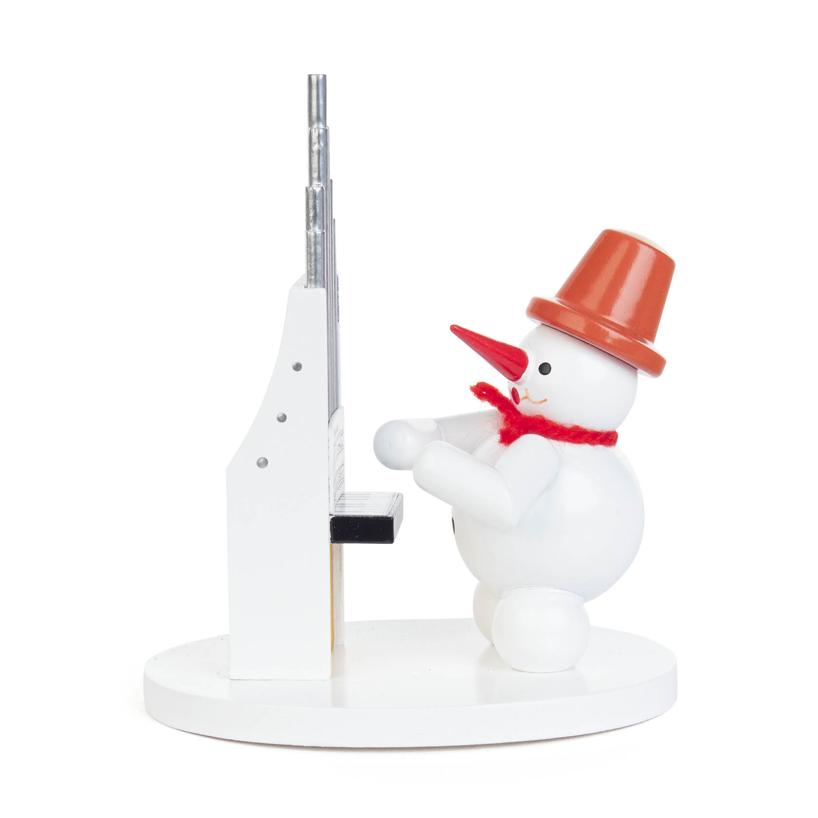A small snowman figurine wearing an orange hat and red scarf is positioned playing a small white organ with pipes.