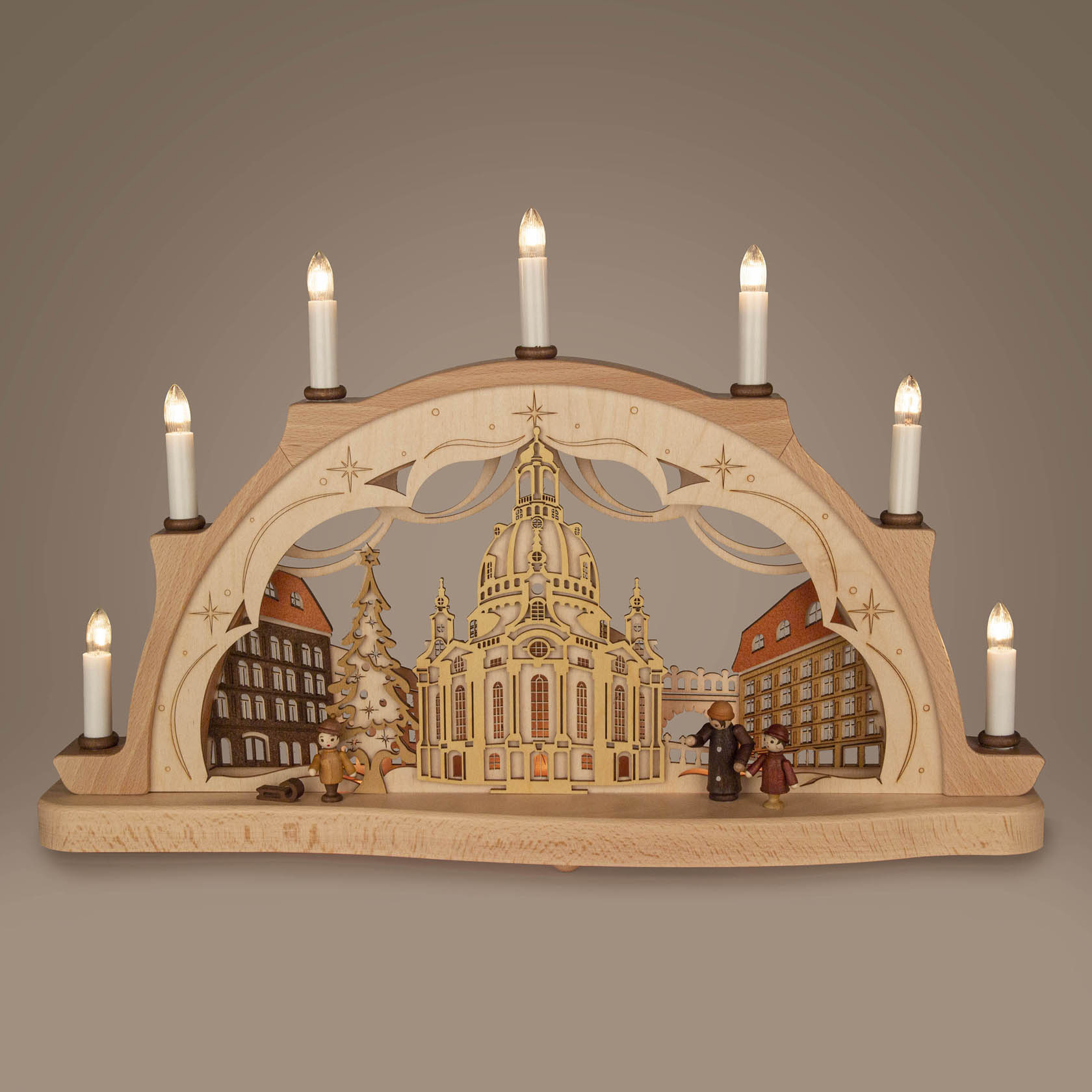 Ein 3D-Schwibbogen mit der Dresdner Frauenkirche, elektrischer Beleuchtung und Figuren vor der Kirche, flankiert von Kerzen.