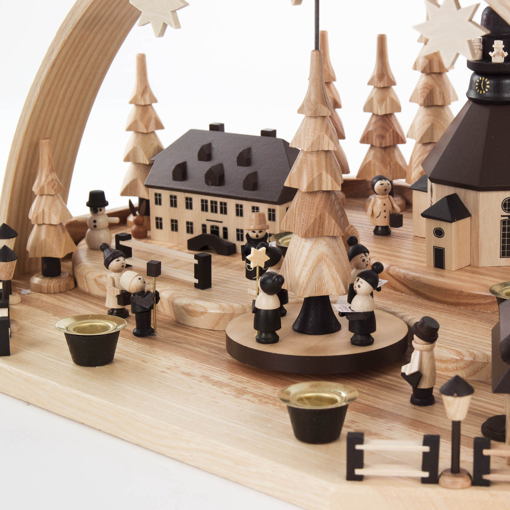 Holzkunst-Weihnachtsberg mit mehreren kleinen Holzfiguren, darunter Frauen und Männer, die Kavaliershüte tragen. Im Zentrum steht ein großer Baum. Umgeben von kleinen, bemalten Holzhäusern und Bäumen.