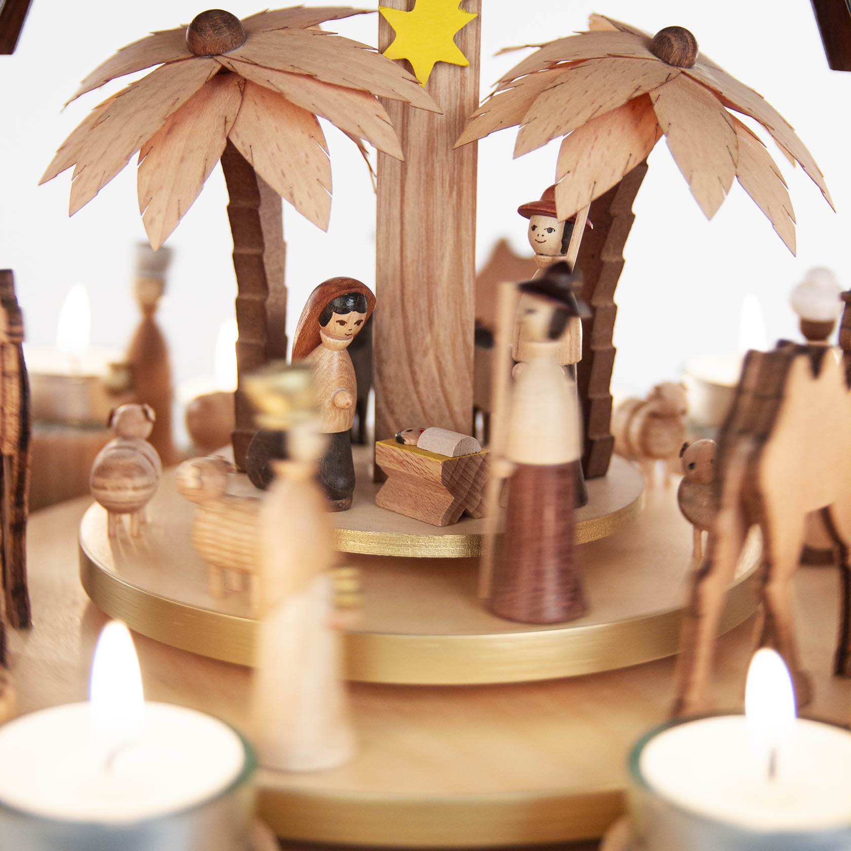 Holzpyramide mit Christi Geburt dargestellt. Figuren aus Holz: Maria, Josef und Jesus in einer Krippe, umgeben von Hirten, Tieren und Kerzen.