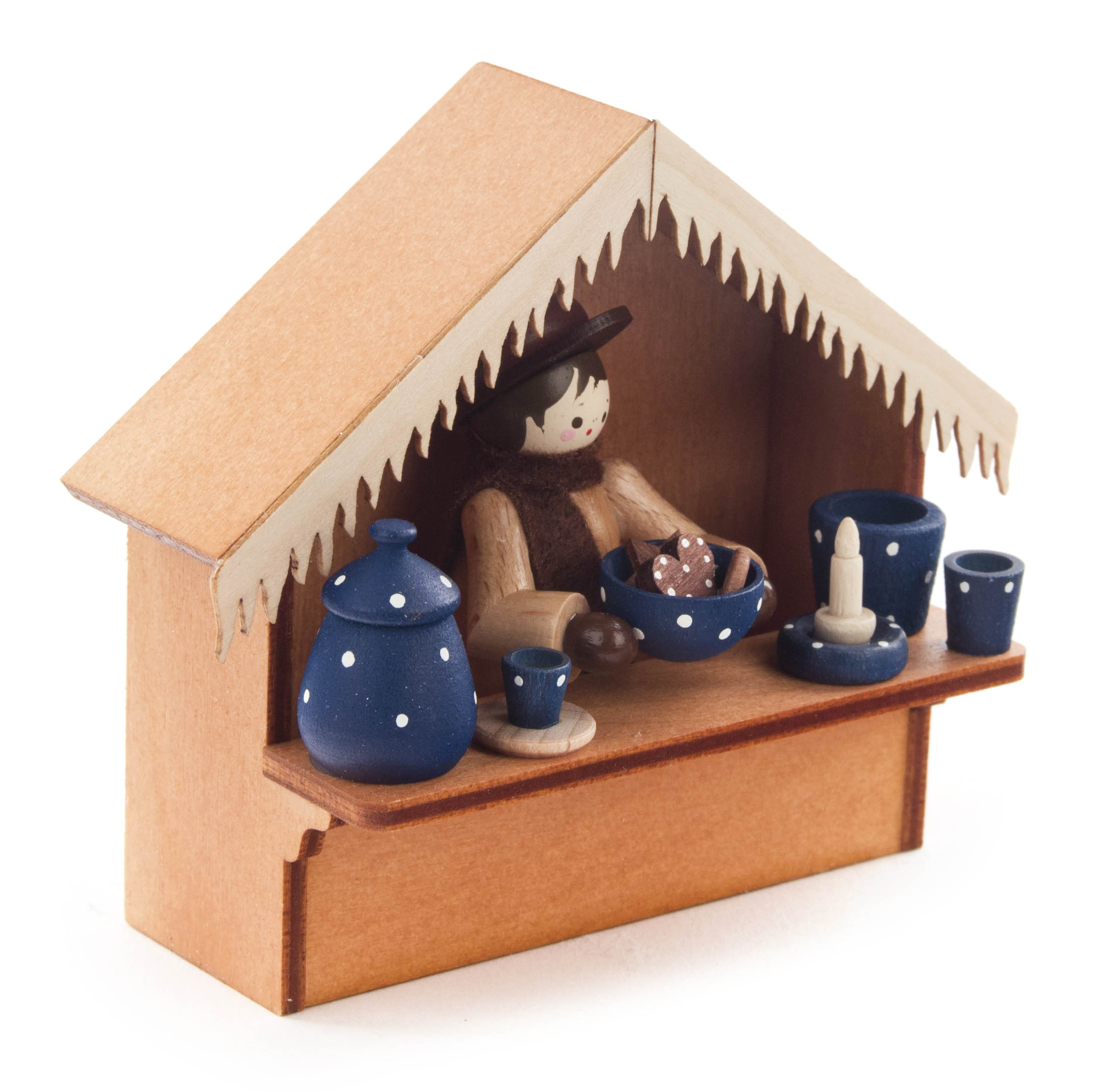 Holzfigur in Stand mit blauer Punktkeramik, Töpfen, Tasse, Schale mit Kugeln und Kerze.