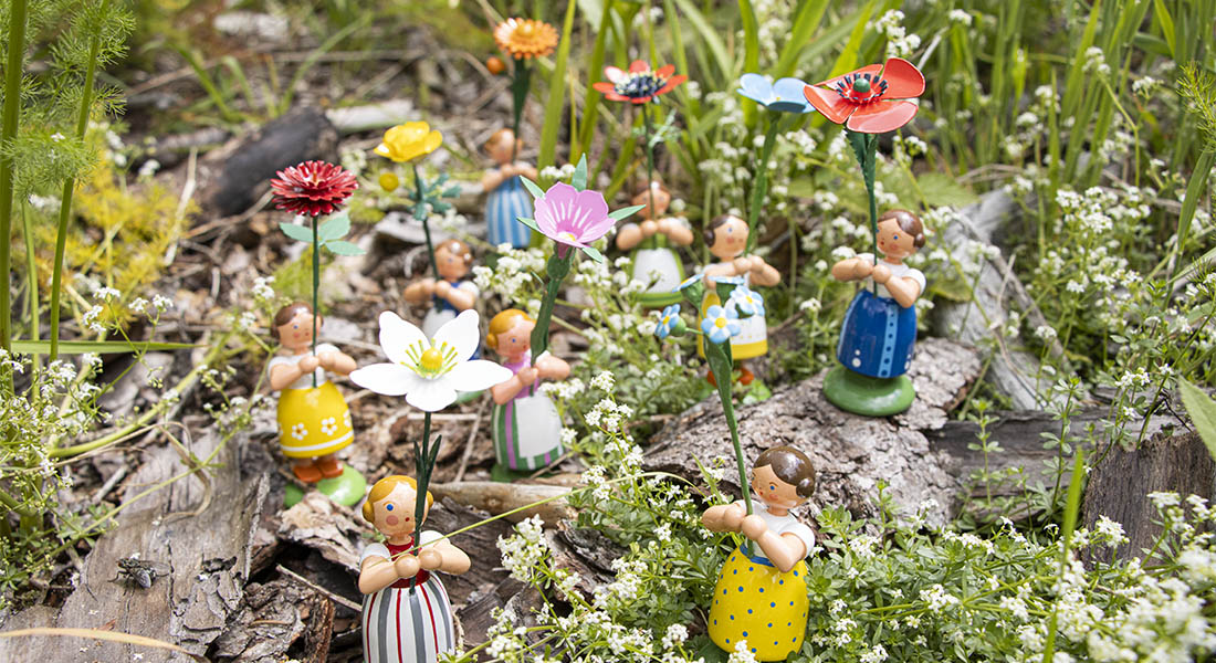 Handgefertigte Blumenmädchen aus Holz mit bunten Blüten als erzgebirgische Frühlingsdekoration